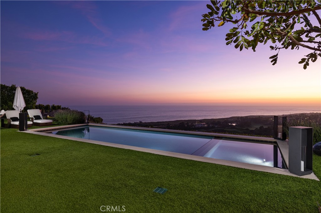 Absolutely breathtaking in their beauty and scope, the unobstructed Pacific Ocean, Catalina Island, sunset, coastline, pier, city light and fairway views from this phenomenal custom residence are only the beginning of your unforgettable journey. Welcome to 5 Del Mar in the gated Estate Collection neighborhood of Newport Coast’s guard-gated Crystal Cove community, where a prized end-of-cul-de-sac location on a hilltop homesite is truly second to none. Showcasing the talents of ETA Architects and Pinnacle Custom Homes, the one-of-a-kind residence reveals a sophisticated, modern aesthetic appealing to the senses with top-tier finishes and amenities enriching sumptuous view-oriented living spaces. A private interior entry courtyard with custom wall fountain blends seamlessly with a formal foyer and a great room that opens via slideaway walls of glass to the courtyard on one side and an ocean-view loggia on the other. The impressive room flows effortlessly to a sleek kitchen with smooth custom wood cabinetry, polished stone countertops, a massive island, generous walk-in pantry and today’s most coveted appliances. Approximately 6,271 square feet, the four-bedroom estate is home to four full and four half baths, an office, bonus room, formal dining room with cross-loin ceiling and stellar views, and a separate second-level apartment-style suite with kitchen and view deck. On the main level, the primary suite opens to the backyard and hosts a fireplace, enormous walk-in closet, and a resort-caliber bath with freestanding tub. The lush, private grounds of the estate embrace almost 20,703 square feet and rival nearby five-star hotels. Entertain in the courtyard, or step outback for magnificent views, a swim in the saltwater pool, relaxation in the spa, and unforgettable times in an outdoor living room with fireplace, built-in grill, refrigerator and ice maker.