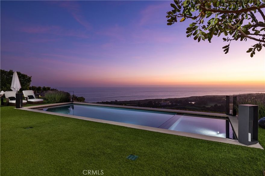 Absolutely breathtaking in their beauty and scope, the unobstructed Pacific Ocean, Catalina Island, sunset, coastline, pier, city light and fairway views from this phenomenal custom residence are only the beginning of your unforgettable journey. Welcome to 5 Del Mar in the gated Estate Collection neighborhood of Newport Coast’s guard-gated Crystal Cove community, where a prized end-of-cul-de-sac location on a hilltop homesite is truly second to none. Showcasing the talents of ETA Architects and Pinnacle Custom Homes, the one-of-a-kind residence reveals a sophisticated, modern aesthetic appealing to the senses with top-tier finishes and amenities enriching sumptuous view-oriented living spaces. A private interior entry courtyard with custom wall fountain blends seamlessly with a formal foyer and a great room that opens via slideaway walls of glass to the courtyard on one side and an ocean-view loggia on the other. The impressive room flows effortlessly to a sleek kitchen with smooth custom wood cabinetry, polished stone countertops, a massive island, generous walk-in pantry and today’s most coveted appliances. Approximately 6,271 square feet, the four-bedroom estate is home to four full and four half baths, an office, bonus room, formal dining room with cross-loin ceiling and stellar views, and a separate second-level apartment-style suite with kitchen and view deck. On the main level, the primary suite opens to the backyard and hosts a fireplace, enormous walk-in closet, and a resort-caliber bath with freestanding tub. The lush, private grounds of the estate embrace almost 20,703 square feet and rival nearby five-star hotels. Entertain in the courtyard, or step outback for magnificent views, a swim in the saltwater pool, relaxation in the spa, and unforgettable times in an outdoor living room with fireplace, built-in grill, refrigerator and ice maker.