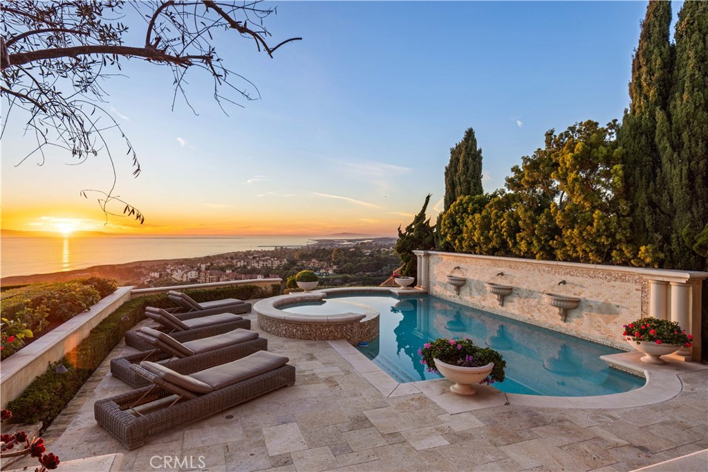 Inspired by the private villas of Europe’s romantic Mediterranean region, this sublime custom residence in Crystal Cove’s guard-gated Estate Collection has it all, from fabulous ocean views and top-tier appointments to generous space and lush grounds. Sequestered on a small cul-de-sac street, the opulent home is poised on a hilltop where unobstructed panoramic views span the azure Pacific Ocean, dramatic canyons, natural hillsides, lush fairways, evening lights, beaches, Catalina Island, sunsets and Orange County’s famous coastline. Grounds extend nearly 21,607 SF and frame the home with formal gardens, custom fountains, a gated entrance, private courtyard, and a resort-rivaling backyard with pool, spa, loggias, a built-in BBQ center and a lawn for elegant gatherings. Glass and wrought iron entry doors open to a circular foyer with illuminated art niches that provides an appropriately impressive introduction to the villa, which reveals seven en suite bedrooms, eight full and three half baths, two offices, a bonus room/loft, and a subterranean level with wine cellar and custom state-of-the-art theater in approx. 11,888 SF. Beyond the rotunda awaits a phenomenal great room that features a high open-beam ceiling and oversized fireplace, and is flanked by colonnade-style halls with stunning cross-loin ceilings. One hall opens to a private courtyard via numerous sets of Palladian-style French doors, and the other offers passage to a formal dining room with patio, and the home’s casual living and entertaining spaces. A great room with built-in entertainment center opens directly to a richly appointed kitchen complete with a separate breakfast room, butler’s pantry, oversized island, built-in refrigerator and a pro-grade Wolf range. This level is also home to the primary suite, which offers an ocean-view loggia, expansive custom closet, and a luxe bath with freestanding tub. Enjoy an eight-car garage, view balconies, and a top-floor bonus room with ocean views.