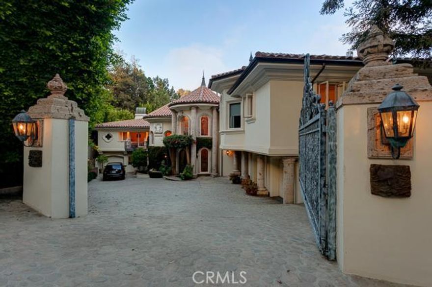 The exterior of this sprawling 7-bedroom, 11-bathroom Mediterranean style estate is adorned with towering pillars, spires, and arches. The two-story living room will leave you breathless. The formal dining room is off the living room and adjacent to the chef’s kitchen, a gourmand’s paradise with a center island. You’re going to love the library, with its built-in bookcases and unique aesthetic. Up the artfully curved stairway, the four en suite bedrooms are spacious and comfortable, with glass doors leading to their balconies.  The master bedroom includes a his/her walk-in closet, and its bathroom features a marble spa tub.  Other bonuses include a wine cellar with refrigeration, a game room with a pool table, a bar, a gym, and seven fireplaces.  The one-bedroom guest house with separated entrance is perfect for overnight visitors. The resort-like back yard offers a pool and spa, a covered dining area, and scenic mountain valley views.  You will never tire of entertaining here and will be proud to call it home.