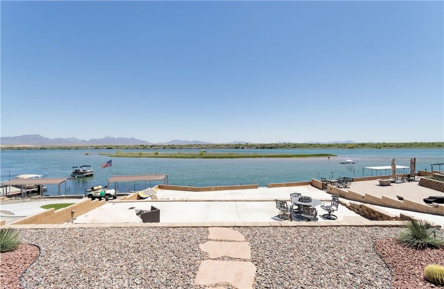 HUGE PRICE IMPROVEMENT! Summer is coming so make sure and check out the coolest house on the river! This exquisite, riverfront home has everything you need to live your best life on the Colorado River! This custom built home comes fully furnished including all furniture, pots, pans, bedding, dishes, glasses, a home computer for your work station! Boasting 3 spacious bedrooms, each with its own en suite bathroom and an additional powder room, this home is designed for comfort and privacy so your guests can feel right at home. The great room has large sliding glass doors that seamlessly blend indoor and outdoor living, providing breathtaking river views and easy access to the large patio and the beautiful 3 tiered backyard. This smart home features the latest in appliances and home automation, ensuring both ease of use and energy efficiency. The kitchen has top notch Jenn Aire smart appliances and beautiful Quartz natural stone countertops. The expansive boat garage measures 23 feet wide by 45 feet deep and offers plenty of storage for watercraft and recreational vehicles. The exterior is as low maintenance as it is beautiful with high quality artificial turf and drought tolerant desert landscaping. Every detail of this home has been meticulously crafted, making it not only one of the most stuning homes on the river but also one if the most livable and easy to maintain. This home truly stands out as one of the finest examples of luxury riverfront living.