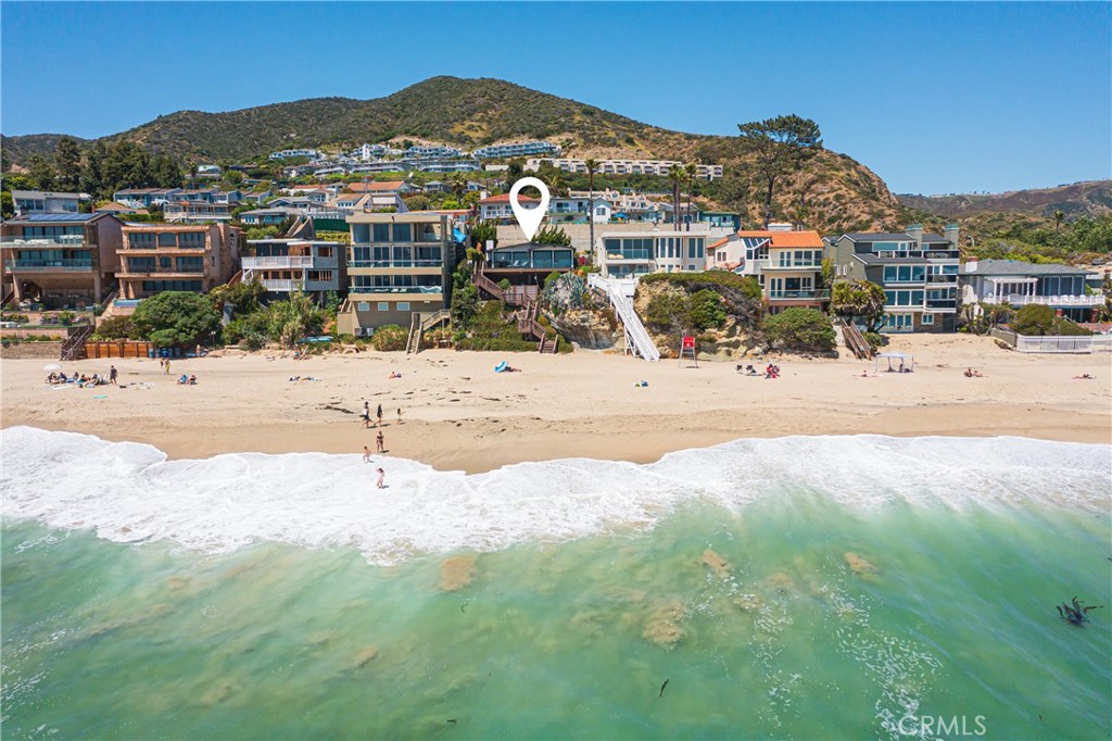 Unobstructed oceanfront views are just one of the countless rewards you will enjoy at this extra-light, exceptionally open Mid-Century Modern home in south Laguna Beach. Featuring private stairs to the sands of Aliso Beach below, the clifftop residence offers panoramic Pacific Ocean views that include breaking waves, sunsets over Catalina Island, and beaches to the north and south. A large front yard with a paver-finished driveway for ample guest parking and an attached one-car garage ensures appreciated privacy from the highway. A gate on the side of the garage opens to the completely private side entrance of the home, which extends approximately 1,536 square feet. Built in 1956, the two-bedroom, two-bath design showcases a recent remodel that maintains MCM style while incorporating modern finishes and fixtures. Commanding sit-down ocean views embellish the entire main living area, where a floor-to-ceiling bookmatched stone fireplace anchors the living room, and vaulted and beamed ceilings soar over the adjacent kitchen and family areas. Floor-to-ceiling windows and glass doors open to a wraparound deck with magnificent ocean views and plenty of room for entertaining. Indoor entertaining is equally impressive thanks to a magazine-caliber kitchen with quartz countertops, glass cabinetry, an island and separate peninsula with bar seating, a wet bar with built-in beverage cooler, and Viking appliances including a built-in refrigerator and six-burner cooktop. Vaulted ceilings continue in both bedrooms, and baths display custom quartz counters and shower surrounds. The primary suite is further enriched with a walk-in closet, LED mirror, two sinks, and a spacious shower. This home’s prime location is minutes from the Montage Resort and golf at The Ranch. Laguna’s Main Beach is only a short distance up Coast Highway, and Monarch Beach and Dana Point await to the south.