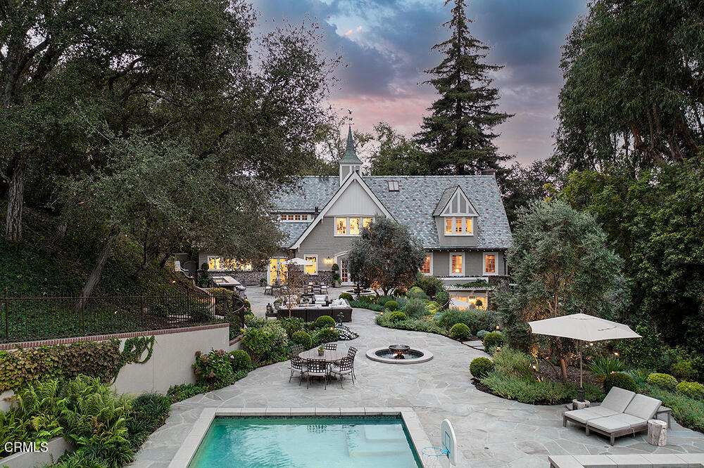 Sited on 1.25 acres of sprawling park-like grounds on the bank of the lower Arroyo Seco, 1240 South Grand Avenue is a 1906 architectural gem designed by Frederick Louis Roehrig. With 6BR,7BA and 7,177 square feet of living space across three levels, this recently renovated estate abounds with amenities. For those looking for privacy and tranquility and the beauty of country living with the convenience of the city, welcome to an enchanting, gated estate that provides a lifestyle of elegance and ease. Past the long private driveway is an English Tudor Revival estate, which in 1906 was commissioned as a 23-room mansion constructed of plaster and brick veneer. Inside, residents are greeted by wood paneling and intricate design details, a testament to the quality craftsmanship of the time. A formal living room, dining room, and library provide tranquil spaces for leisure and entertaining. Stunning architectural features include the generous use of Oak and Mahogany, tall ceilings, spacious and well-appointed public and private rooms, 2-built-in bars, oversized fireplaces, and long French-styled windows. A gourmet kitchen with plentiful custom cabinetry, imported tile and fixtures, a large island, commercial-grade appliances, and a large butler's pantry opens to a second outdoor kitchen complete with a plethora of stainless appliances and an expansive patio and seating area. An office, powder room, and bedroom suite complete the estate's main floor. A passenger elevator services the three floors of the residence, including the lower level that encompasses a built-in Oak bar and media room with surround sound and three television screens, a marble powder room, a temperature-controlled wine room, a cavernous laundry room with space for storage, and a spacious guest suite with a whimsical white tiled bath, a walk-in dressing closet and French doors that open to the expansive rolling green lawn. The private third floor features the primary suite with a fireplace, two custom-designed dressing rooms, and two marble baths. Each additional bedroom suite offers walk-in closets and views. Outside is a Shangri-La lifestyle, anchored by an 870 square foot pool house with a vaulted cathedral ceiling, blue stone flooring, a large fireplace, and French doors to the saltwater pool, oversized spa, and bountiful vegetable gardens, seasonal blooms, and bursts of color from every corner. A 1,221 sqft 4-car garage and workshop with attic storage complete the estate.