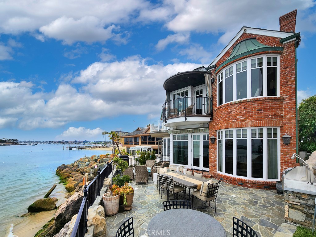 It simply doesn’t get better than this. A true stand-out along Southern California’s world-famous coastline, this extraordinary waterfront estate is set directly on a rocky bluff overlooking Newport Bay in China Cove. Views are incomparable by day or night, with colorful sailboats and magnificent yachts gliding along the main channel in the foreground, festive holiday boat parades in December, and the Pacific Ocean, Balboa Peninsula, amazing sunsets and evening lights providing a kaleidoscopic backdrop for refined luxury living in Corona del Mar. Located on Shell Street, one of the most exclusive addresses in the region, this exquisitely crafted New England-inspired masterpiece takes full advantage of its setting with a massive stone terrace that complements every occasion with stunning views, a custom built-in BBQ and the soothing sounds of the bay lapping at the rocks below. Centered around a sweeping multi-level floating spiral staircase, the opulent residence measures approximately 4,040 square feet and hosts four bedrooms and four- and one-half baths. The main level showcases a fireplace-warmed den with handsome wood paneling, built-in media, a two-story ceiling and a 160-bottle temperature-controlled wine cellar. Memorable entertaining is easy in formal and casual living areas that are richly detailed with wood and brick floors, custom crown molding, custom marble finishes, tray and barrel ceilings, extensive built-ins, handcrafted millwork, custom window treatments and stylish lighting fixtures. A fully appointed chef’s kitchen exhibits a large island, white cabinetry, stone countertops, and top-of-the-line appliances including built-in beverage coolers. Equally impressive, the top-level primary suite features a large bay window, two sitting areas, a view balcony, boutique-style walk-in closet, and an opulent ensuite bath. Curb appeal is unmatched, with classic seaside architecture enhancing a column-lined covered entry porch, handsome brickwork and access to a subterranean garage. Limited to just a few stunning residences, Shell Street is close to Corona del Mar’s main beach, village shops and restaurants, golf at Pelican Hill and high-end shopping at Fashion Island. Outstanding schools serve the community, and miles of beaches and gorgeous coves extend to the north and south.