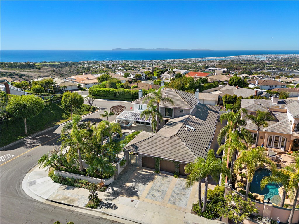 Spy Glass Hill custom estate featuring 5040 sq. ft. on a rare 15,740 sq. ft. corner lot with gorgeous panoramic views of Newport Coast, the harbor, and the mountains to the east. Original home underwent an addition adding a second larger primary bedroom on 2nd level and updating the kitchen. Open floorpan features 2 story grand foyer and spacious great room with adjacent dining room. Multiple sliding doors open the home up to the west to capture stunning ocean views and majestic sunsets. Chef's kitchen features Viking/Sub Zero appliances, island with prep sink, and sun drenched dining nook with corner windows to enjoy the views. Opulent family room/den has built in bar, separate wet bar, marble fireplace, and custom wood work throughout while opening to the pool and spa for indoor/outdoor entertaining. Spacious yard features a southwest facing pool, BBQ island, louvered patio area, and stone fireplace. Expansive primary suite on 2nd level has large picture windows to capture the view; also features a spacious siting room, fireplace, oversized walk-in closet and large balcony. Formal office with built-in desk opens to balcony as well. Home has 2nd kitchen that would make perfect in-law suite or 1 bed studio. Remodel or re-imagine this truly one of kind property in one of the most desirable neighborhoods. Wonderful location near Fashion Island, Newport harbor, shops and dining.