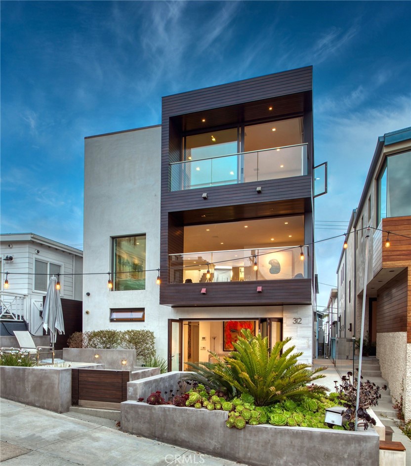 17th Street walk street is one of the most exclusive streets in Manhattan Beach due to its unparalleled panoramic ocean views and proximity to the charming beach town. Among its highest points is a Modernist home completely redone in 2011, designed by Abramson Architects—a winner of the prestigious American Architecture Awards® in 2020—and Dan Burns who was in charge of the interior. Approx 3600 sq feet, this 3-bedroom, 4-bathroom home features sharp, clean lines in luxurious, organic materials—sophisticated mahogany, tumbled limestone and smooth stucco on the exterior. The front door, in steel and walnut, opens into the foyer—a cathedral-like space. There are ocean views throughout the home’s levels culminating in a secluded rooftop deck where you can relax and entertain over a panorama of the Pacific Ocean coastline. The charm of walk-street living is the open-air mingling of interior and outdoor spaces, resulting in gatherings over ocean views and quiet moments watching waves from your private perch just two blocks from the beach. Folding glass connects the patio with a flexible, sunlit room that functions as a gathering spot, en-suite bedroom or office. On the same floor is another bedroom suite w/ walk-in closet and bathroom bathed in onyx. The heart of the residence is on the second floor, a serene open layout of living spaces. There’s a family room, formal living room, dining room and two-story kitchen—with light from a dramatic network of windows and skylights above. Walls are Venetian plaster, and the cabinetry is a mix of walnut and high-gloss white fashioned by German makers LEICHT. Appliances are Gaggenau and Miele, surrounded by pristine white walls and countertops. On the top level is the private primary retreat. The bath showcases Italian marble, soaking tub, and a dual vanity wrapped in mahogany. Steps away, the bedroom is encased in glass and walnut where an ocean view deck links by way of floor-to-ceiling glass. It’s also home to one of the residence’s most standout features: a private walkway to peer down at living spaces below, or head to the rooftop deck. The deck, approx 500 sq ft with elevated sunning deck, BBQ, ice maker and refrigerator, allows you to spend time amid scenes of sky, mountains and waves. There is a synthesis of fine design and high end materials that distinguish this residence, creating a hyper-sophisticated home base where you can live in quiet luxury, entertain in high style, or stroll to the beach or town.