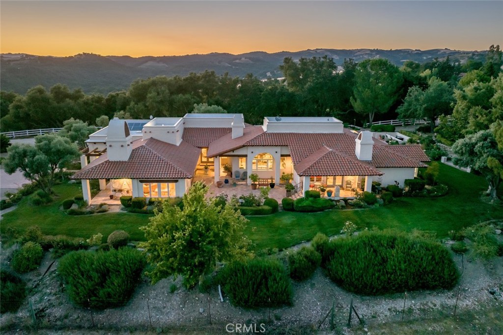 Experience the breathtaking beauty of ever-changing 360 degree panoramic views that unfold from the mesmerizing hues of sunrise to the enchanting tranquility of sunset on this expansive 105 acre estate with a custom mission-styled single-level home offering unparalleled luxury and comfort that seamlessly blends timeless design, modern amenities, and the natural beauty of the site. With 51+ acres of land, established by a technical report, suitable for planting, the potential for crafting your own vineyard is yours to explore. Paso Robles Willow Creek AVA, which is known for a cooler climate, continues to have some of the highest quality and highest scored award-winning wines in the region. Gentle sloping topography and soil conditions known in the area can make for successful grape production. The home has meticulously landscaped grounds, courtyard, and a gorgeous built-in and solar powered swimming pool featuring a waterfall and ample entertaining areas. The home exudes warmth with four fireplaces, multiple skylights, exposed wood ceilings, newer Pella wood-framed casement windows, Pella doors, and Saltillo-tiled floors. The family room comes with a wet bar, fireplace, and a dining area with built-in window seating. The living room offers multiple seating areas and is the perfect gathering spot with a fireplace. The impressive remodeled kitchen boasts a porcelain tiled floor, UK Small Bone Co. cabinetry, Miele and Gaggenau ovens, a breakfast nook, and several stations for the chefs. With three spacious bedrooms and four bathrooms, including luxurious en-suites, this residence offers elegant living for all. The main suite has views of the atrium and comes with a gas fireplace and a private patio. The bathroom has dual Beaumaniere limestone counters, a large shower, and ample closet space. A three-car attached garage and a separate 10+ car garage (3450 sq ft) w/ hydraulic lift, provides ample space for your vehicles, equipment, and hobbies. Also included is a large equipment storage building (5200 sq ft) and a horse barn (2400 sq ft) with paddocks along with sufficient solar panels to serve the property. Situated just 10 minutes from Highway 101, you'll have easy access to all amenities while savoring the Paso Robles lifestyle, with travel to SLO, Morro Bay or Cambria a mere 30 minutes away. The paved access and security gates ensure privacy. Enjoy waking up to stunning views of wildlife, oak trees, and vineyards everyday. Templeton school district.