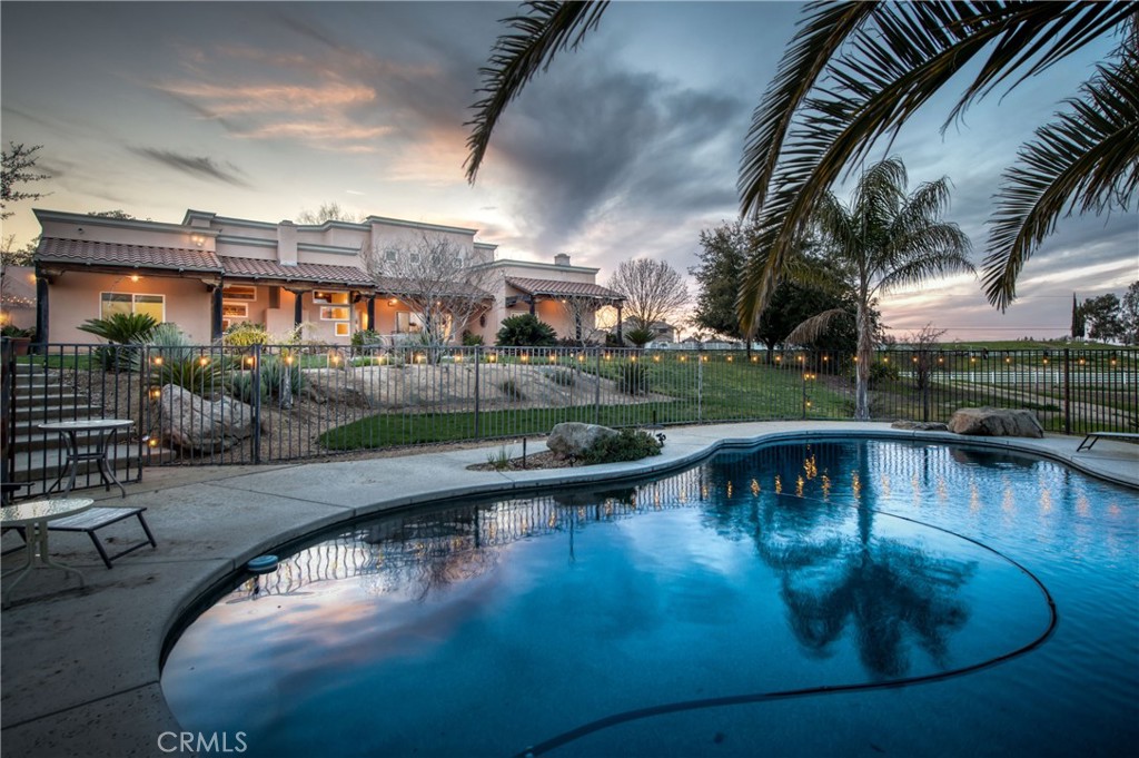 Welcome to this one-of-a-kind home that combines modern amenities, thoughtful design, and old-world charm, look no further than this gorgeous 4-bedroom, 3-bathroom, 3,330 sq. ft. property with a 600 sq. ft. detached in-law suite with a private entrance offers the perfect blend of independence and togetherness for a multi-generational family. Built in 2001, this Santa Fe-style estate features panoramic views of the foothills and is nestled on 5.4 acres of lush land. The private drive leads to a stunning entrance featuring a custom-made Mahogany door that welcomes you into the private compound. The home's interior boasts southwestern details and contemporary finishes, including hand-carved posts, rustic wooden beams, and corbels imported from Taos, New Mexico. Custom cabinetry, granite countertops, and modern appliances make the kitchen both inviting and functional. The spare bedrooms are bright, roomy, and overlook the impressive backyard. The spacious Primary suite comes complete with exposed beams, an Aspen T&G ceiling, a wood-burning fireplace, and private doors that lead into the backyard. The adjoining bathroom includes a full shower, mission-style tile, and elegant fixtures. The backyard is an entertainer's dream; the custom pool and inviting outdoor areas create an ideal backdrop for intimate gatherings and expansive parties alike. Owned solar 5.8 kw/36 panels, a separate 1,200 sq. ft. shop, and a newly installed 556 ft. well. Buyer to verify square footage.