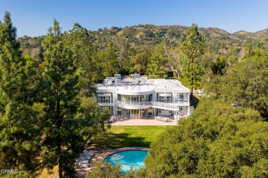 This contemporary masterpiece was custom-designed for the daughter of Robert E. Langdon, the architect of Getty Villa against a mountain backdrop in 1991 on a 1.8-acre lot (approx). The upper floor contains four elegant bedroom suites. The master suite features WetStyle luxury bathroom M Collection, sauna, gym, circular terrace, and a flying bridge celebrating gorgeous mountain views. Laundry room, locker room, and an open office conducive to creativity complete the entry-level floor. An open staircase takes you to the living room with its dramatic ceilings and glass walls blending the interior space with its exterior landscape surroundings. A state-of-the-art Poggenpohl kitchen features a 6'x13' island and Gaggenau, Miele, and Wolf appliances. The open floor plan connects the elegant living room, formal dining, kitchen, informal breakfast room, great family room, and a guest suite. The lavish park-like grounds offer an oversized patio, fireplace, BBQ, expansive circular saltwater pool with water slide, spa, fire pit, waterfall, vegetable garden, fruit trees, children's playground, vineyard, and peaceful trails covered by mature oak trees. Two stunning detached structures featuring a guest suite and an office/music room with bath flank the property's gated entrance to a 6,000 sq. ft. (approx.) motor court and a 3-car garage. Outstanding La Canada Schools.