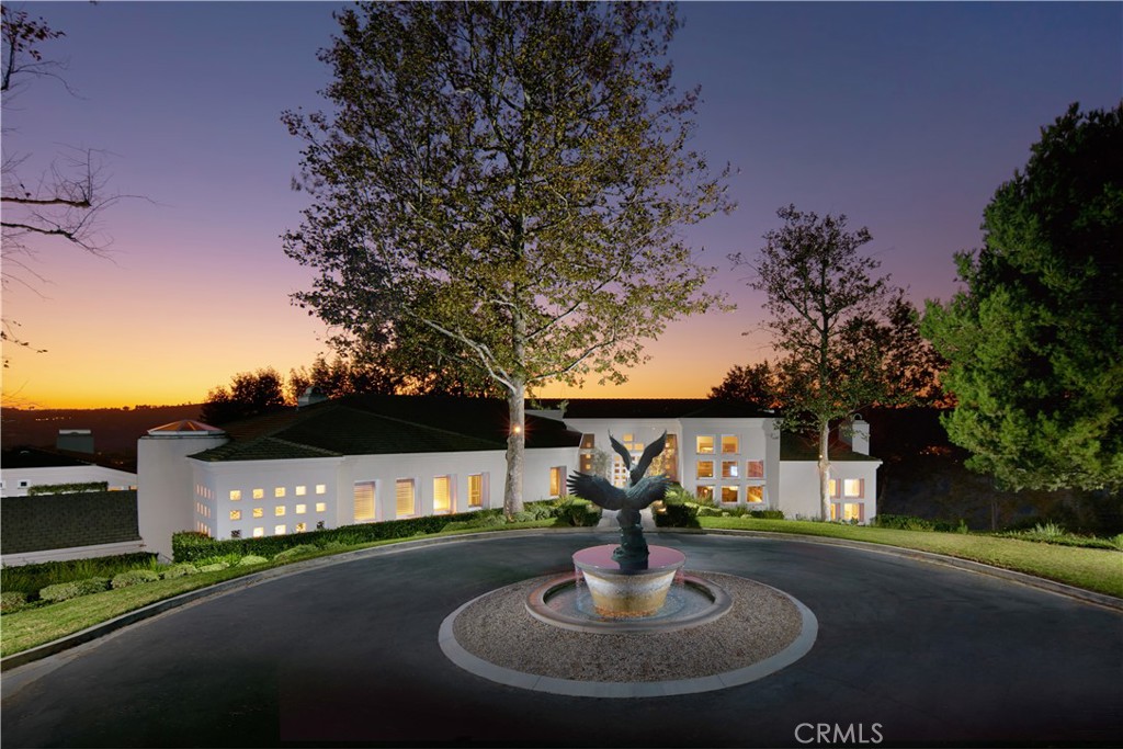 Presenting approximately 176 feet of view frontage overlooking the beautiful grounds and golf course of Marbella Country Club, and the stunning sunsets over the rolling hills of San Juan Capistrano, this one-of-a-kind legacy estate is situated on an approximately five-acre lot behind the exclusive 24-hour guard-gated Hunt Club community. This stately residence offers unparalleled privacy, introduced by an approximately 400-foot, curvilinear, tree-lined, separately gated driveway. Enclosed within are stellar amenities, including a step-down wine cellar and a detached two-bedroom guest house. Designed by architect Gilbert Aja and remodeled by master builder Tony Valentine, the six-bedroom home features artisanal touches like high ceiling beams, wood and stone flooring, skylights, and tray ceilings. The entryway showcases modern architectural elements, which carry through the stair hall to exterior doors and windows, and are repeated in the custom zero-edged pool. The entry level includes two ensuite bedrooms with large walk-in closets, a spacious office with a fireplace and built-ins, and an elegant primary suite featuring a shell-shaped walk-in shower, a dual-sided fireplace serving both the bedroom and the large sitting room with built-in shelving, two oversized walk-in closets, and a private balcony. Downstairs, the gourmet kitchen impresses with Bosch and Miele appliances, an eight-burner stove with a griddle, a BlueStar range, and a large island with a sink. The kitchen nook offers seating for seven, and a kitchen bar seats four. Two opulent living rooms and a formal dining room all enjoy private views of the golf course and mountains. Additionally, there is a laundry room, a second office, and an ensuite bedroom. Separate from the pool lawn is an approximately quarter-acre recreational lawn, ideal for all types of sports and entertaining. This idyllic, tree-lined sanctuary boasts a cozy fire pit, built-in BBQ, and ample seating, creating an inviting atmosphere for gatherings. Enjoy large, covered patios, a saltwater pool and spa, water features, and built-in heaters. The separate guest house is a private sanctuary, featuring a dining room, a kitchenette, a wet bar, and two fireplaces. Despite its desirable privacy and tranquility, this residence is just minutes from trails, shopping, dining, and beaches.