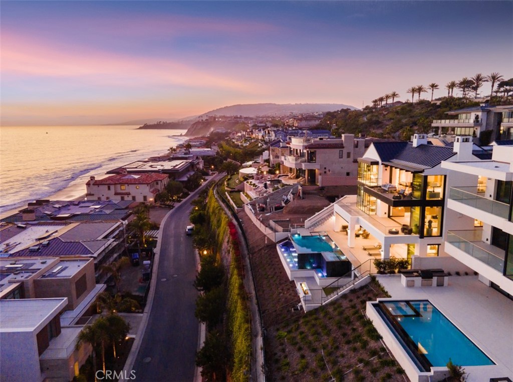 From its awesome second-row perch above the mercurial Pacific Ocean, this unparalleled custom estate in Dana Point’s The Strand at Headlands redefines luxurious seaside living. Ocean, whitewater, shoreline and evening-light views will be enjoyed from nearly every indoor and outdoor vantage point of the residence, which showcases the talents of award-winning Brandon Architects and Hawk & Co. interior design. Floor-to-ceiling windows, slide-away glass doors, skylights, towering ceilings and generously sized living spaces combine to create a breezy, sophisticated vibe in the home. Discover 5 ensuite bedrooms, 8 full and 3 half baths, a media room, wine cellar, bar, theater, game room, gym and optional office in approximately 8,219 square feet. Served by an elevator, the 3-story floorplan welcomes guests on its main/2nd floor with an atrium-style foyer leading the way to a formal dining room with sliding doors for privacy, a great room, breathtaking island kitchen with secondary butler’s kitchen, and access to a the ocean-view cabana, pool and spa. The infinity pool and spa create a cascading waterfall that adds tranquility to a lower sun deck. Ocean views are also enjoyed from a balcony off the master suite, which exhibits a sitting room with fireplace, and a stunning bath with dual-walk-in closets and a massive glass-enclosed shower and tub space. Folding doors open the office to a front patio, and a 5-car garage includes a lift.