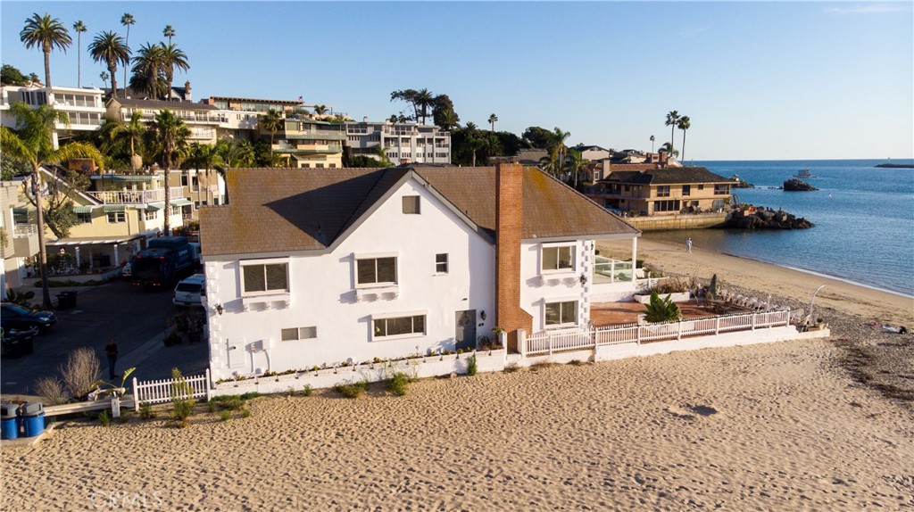 CHINA COVE: Corona Del Mar beach house in coveted China Cove beach is an end house with neighbor on one side and sand on the other side. Fully renovated in 2001 and designed with Feng Shui. You'll find marble floors through-out the main floor. From the living room and dining room you can exit the french doors out onto the outdoor brick patio that opens up to the sandy beach. For colder nights, enjoy the large fireplace in the living room while viewing the spectacular views of the boats and sea life. The kitchen was updated 2 years ago with white granite counters, a new electric stove and kitchen sink. The downstairs bathroom w/ long shower opens up to the side house so that you can swim in the ocean and then wash off all the sand. Washer and dryer located in downstairs bath. Dryer can be electric or gas.
The second floor has hard wood flooring, 4 bedrooms 2 baths and a sitting room. The Master Bedroom with en suite and adjoining bedroom have beach-front views from private balconies, while the sitting room also has beach-front views. Upstairs bathroom has jetted tub and one of the two back bedrooms also has a balcony.
Access to the third floor is through what looks like a closet door but is actually the 2nd staircase on the 2nd floor. There you will find the attic runs the entire length of the home and is fully lighted and tall enough to stand and walk. This space may be used for storage, or a hobby room, or office, or workshop. The roof has solar panels, and the windows through out the home have outdoor electric shutters to maintain cool, heat and security.
The spacious 2-car garage w/ finished flooring has plenty of room for 2 cars, extra fridge, surfboards, beach toys and other storage. 1 additional parking space in front of the garage .
Savor the views of the beach, jetty, boats, Catalina Island, bay, and sunsets from the main floor, second floor and balconies. Enjoy the boat parade and host a holiday party.
China Cove is nestled between Ocean Blvd and the Channel shoreline and offers an air of privacy rarely available in seaside communities. Less than 40 properties are in China Cove and has 2 secluded sandy beaches, one with volleyball court. Live the California dream, breathe in the fresh salt air and see the dolphins and seals swim by, commune with nature and enjoy close restaurants, shopping and beaches.
The China Cove beach has a roped off swimming beach, which is safe for kids and adults.