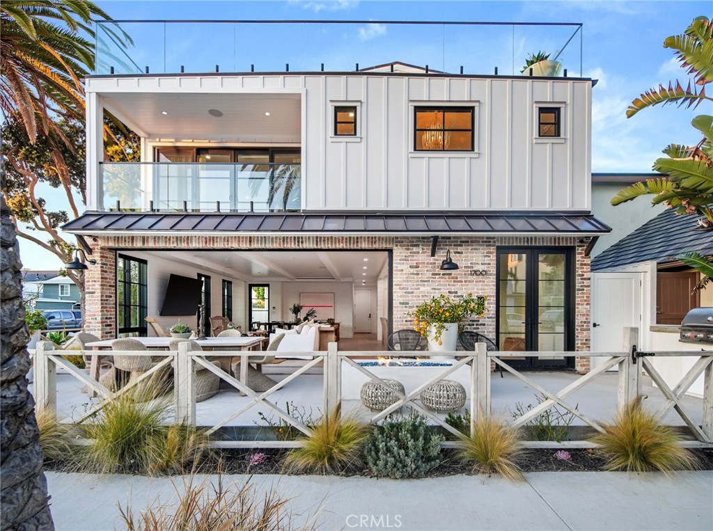 Stunningly warm coastal farmhouse enveloped by iconic palm trees, situated on an oversized wide corner lot on the prestigious Peninsula Point. Offers magnificent views spanning from the Pacific Ocean to Mount Baldy and is just steps from the sand. The 3-level home boasts pristine design and high-end finishes, including inviting white European oak floors outfitting the interiors, coupled with various specialty tiles throughout the bathrooms. Custom White shiplap walls add another appealing component to each floor in the house. A chef’s kiss to the kitchen, it is topped with Calacatta marble and designer brass hardware with a large cascading waterfall island, large farmhouse sink, sleek white cabinets, and high-end appliances. The main level, with an open floor plan, comes replete with an airy and light-filled living area, a spacious dining area accentuated by a rustic white brick feature wall, cozy bar area, laundry room with double stacked appliances and powder bath. The custom pocket doors open the main level to the lower terrace boasting a fire pit, grill, and plenty of space for entertaining guests. The sleek primary suite includes large private balcony with breathtaking ocean view, spacious walk-in closet and a luxurious spa bathroom with dual vanities, a large soaking tub, oversized walk-in shower clad in marble and encased in glass doors, custom wood cabinetry with marble countertops, chic herringbone tile flooring, and mood lighting. The three spacious guest bedrooms luxuriate custom features throughout with one enjoying its own private balcony. The upper level has a custom-built minibar and a full bathroom complete with signature red-bricked walls. Behind folding glass doors, this level opens up to arguably the largest roof deck in the area. The magnificent 1,000+ sq. ft. rooftop terrace is truly an entertainer's dream with its multiple covered and uncovered lounging areas, fire pit, and a built-in grill and mini fridge, overlooking the ocean, city and snowcapped mountains. A 3-car garage with Tesla/charging port, Sub-Zero fridge completes this rare offering, making it one of the best options out there for any discerning buyer.