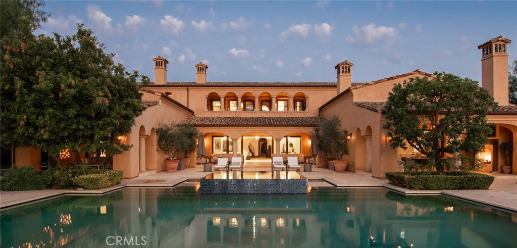 Set within the prestigious, guard-gated community of Shady Canyon, this exceptional estate spans nearly an acre on a highly sought-after corner lot. Elevated on a scenic promontory, it offers breathtaking panoramic views of lush rolling hills, tranquil canyons, and sparkling city lights. This custom-designed residence epitomizes the height of luxury and sophistication, perfect for both grand entertaining and refined everyday living. Boasting an expansive 15,024 square feet of living space, the main residence features 7 generously appointed bedrooms, 9 full baths, and 4 half-baths, complemented by a detached casita with its own full kitchen, living room, and private entrance. Highlights include a main-floor primary suite, a state-of-the-art theater, a grand ballroom, an elevator, a fully-equipped gym with sauna, and a walk-in wine cellar. The meticulously landscaped grounds are a sanctuary unto themselves, offering private gardens, serene courtyards, loggias, and a resort-style pool and spa. A charming cabana with a cozy fireplace, built-in barbecue, and inviting fire pit area create an ideal setting for both relaxation and entertaining. Generous parking space featuring a 5-car garage and an expansive motor court, all behind a private gate for added privacy and security. Perfectly located just moments from Orange County’s finest beaches, top-rated schools, and world-class shopping and dining, with convenient access to major freeways. This rare estate combines unparalleled privacy, exceptional amenities, and a truly enviable location.