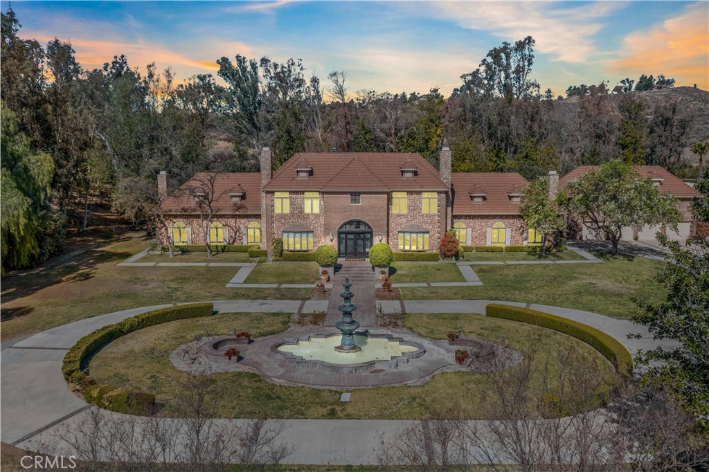 ***A Masterpiece of Elegance and Serenity in Temecula Wine Country*** Welcome to this extraordinary luxury estate, offering 10,000 square feet of opulent living space on over 10 private, tree-lined acres in the heart of the Temecula Valley Wine Trail. A gated entry opens to a meandering driveway that traverses the property leading you to a grand roundabout featuring a 20-foot water fountain—your first glimpse of the estate’s timeless sophistication. Step through brand-new double doors, adorned with wrought iron accents, into a grand foyer showcasing a massive chandelier & marble floors that extend throughout the main level & up the sweeping staircase **Every detail of this home has been designed to inspire** The main level features an impressive ballroom with four chandeliers, a wood-beamed ceiling, a floor-to-ceiling brick fireplace, & courtyard access. A stately office offers a cozy fireplace, hardwood built-ins, & a five-panel bay windows framing stunning views. The formal dining room, with its own fireplace, flows seamlessly into a fully renovated kitchen featuring waterfall marble countertops on a sprawling center island with bar seating, white & blue shaker cabinets, commercial-grade appliances, a coffee bar, breakfast nook, & dual backyard access. A library with fireplace & hardwood walls & built-ins, a massive family room with fireplace, full bar & a spacious laundry room round out the main level. A brand-new elevator provides effortless access throughout the home. Upstairs, a master suite has a private retreat with fireplace, luxurious bathroom featuring a huge natural stone shower, soaking tub, dual vanities, & his/hers closets. Two junior suites with private baths—one with a balcony overlooking the pool—& a functional sauna complete this level. The enchanted 10-acre grounds are awe-inspiring. Highlights include a rolling hills executive golf course, a half-acre pond with an island & water features, a thriving grove of various fruit trees, & three cleared acres ready for planting vines or whatever you so desire. The upper grounds feature a newly renovated Olympic-sized pool & spa plus a sand volleyball court, & space for a pickleball court. Above the four-car garage is an 1,100-square-foot ADU/Casita with a private entrance, two master suites with private baths, a kitchenette & laundry—perfect for multi-generational living or guests. Surrounded by award-winning wineries, this estate offers unparalleled luxury in Temecula Wine Country.