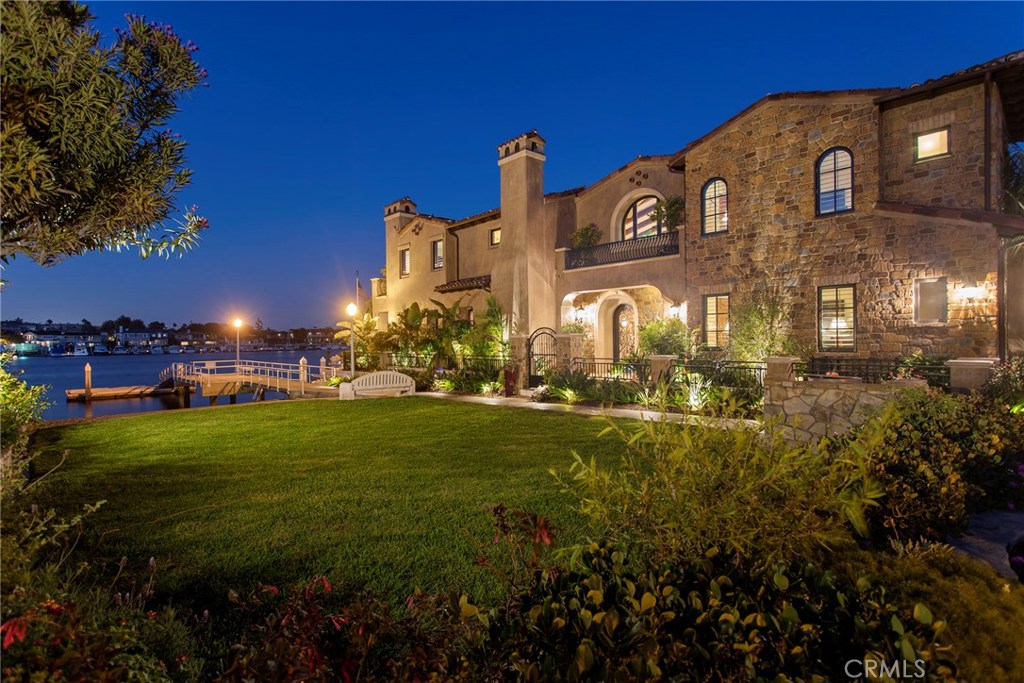 Sandy beaches and ocean breezes await you with this incredible Lido Island home, sitting on 60 feet of Newport Channel waterfront. Built on two lots, the impeccable Tuscan estate is overflowing with rustic style and amenities, like exposed wood beams, arched windows, wrought iron banisters, stone and wood floors and custom built-ins. This home truly embodies the Lido lifestyle and offers over 5400 sq. ft. of living space right on the water and next to a beach. The home boasts 4 bedrooms including a luxury master with his/her spa style en-suites, a main floor bedroom, 4 fireplaces, an elevator, a multi-purpose large laundry/craft room, gym space, and an office. The kitchen is gourmet, flowing out to the covered patio for indoor/outdoor entertaining and dining al fresco with the tranquility of the water rippling outside. This house features plenty of garage space and nearly 500 sq. ft. of basement, and the private dock offers two huge spots, for around 70’ vessel on the east side and a 50’ vessel on the west. Imagine walking to excellent restaurants, shops and activities. With this beauty on Lido, this is reality. Enjoy the ultimate in beach living in this magnificent home in Newport.