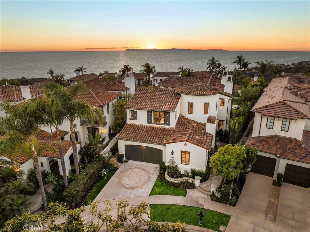 This newly renovated gem in the prestigious guard-gated community of Crystal Cove offers is a rare combination of elegance, charm, and privacy. Set on a unique pie-shaped lot spanning 7,621 +/- square feet, this 5 bedroom, 5 bathroom residence provides an expansive layout, captivating views, and a tranquil ambiance. This stunning home invites you in through a grand foyer with soaring ceilings and a gracefully curved illuminated staircase. The wood floors flow seamlessly throughout the main living spaces. The heart of the home is the vast open-concept great room, dining area, and family room—perfect for both relaxed living and elegant entertaining. Breathtaking ocean views are framed by a picture window at the far end of the great room, where the horizon meets the beauty of Catalina Island. The fully renovated kitchen is a dream, featuring a porcelain-topped island with wood cabinets, a Wolf 6-burner range with dual ovens and a grill, a wine cooler, and custom cabinetry and a cozy dining nook adjoins the courtyard. This home is designed with both style and function in mind. The 5 spacious bedrooms, 4 of which are en suite, with two conveniently located on the main floor, offer flexible options for use as a home office or gym. Upstairs, two secondary suites and the luxurious primary suite provide ultimate comfort and privacy. The expansive primary suite feels like an upscale boutique hotel with a private covered deck that offers stunning white-water views stretching to Palos Verdes. Inside, the spa-like ensuite bath boasts a soaking tub, dual vanities, a makeup vanity, and a generous walk-in closet, all bathed in natural light. A bonus area on the upper floor provides an additional space for relaxation or entertainment, with possibilities for a 6th bedroom. The private backyard's wide-open views and peaceful surroundings offer the perfect backdrop for unwinding after a busy day. Living in Crystal Cove means more than just a luxurious home; it’s a lifestyle. Enjoy 24-hour guard-gated security, access to the exclusive Canyon Club with its pool, spa, fitness center, playground, sports courts, and scheduled activities. Crystal Cove is ideally situated just a short stroll from the Crystal Cove Shopping Center, with private walking access to the pristine Crystal Cove State Beach, scenic parkland, and historic district. With Fashion Island, Laguna Beach, and world-class dining and shopping options just minutes away, this is coastal living at its finest.
