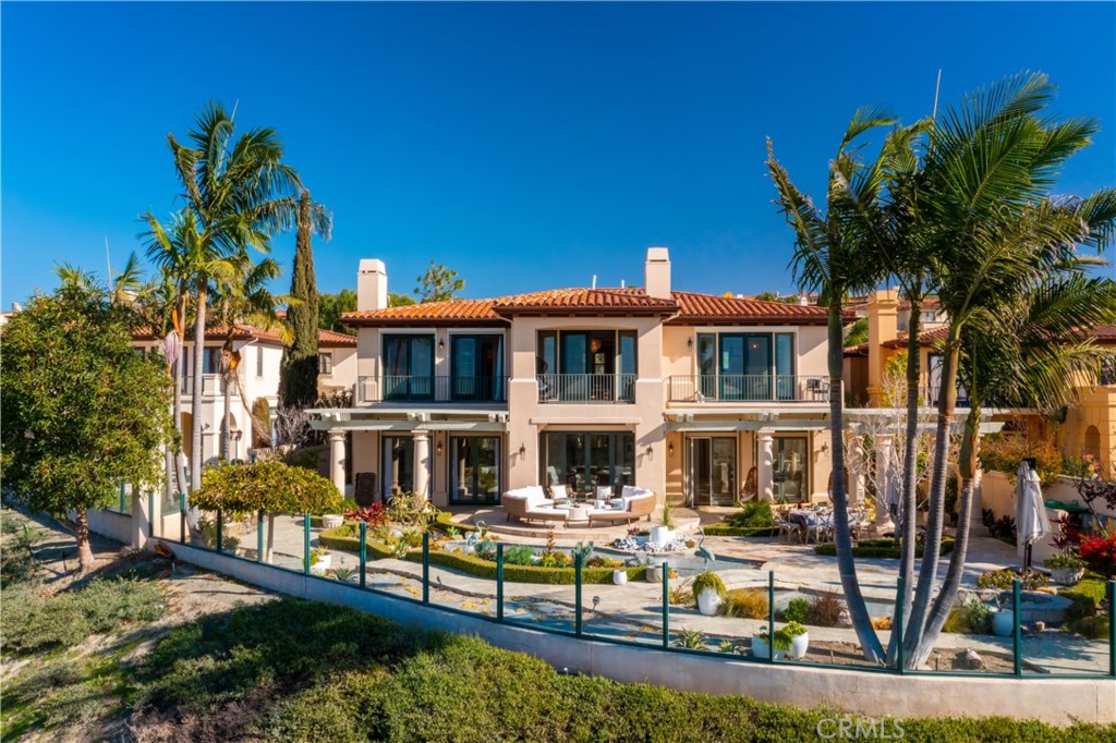 Presenting the epitome of sophisticated coastal design, 5 Via Naples is situated on what is considered to be the community’s most coveted parcel of land. Perched out beyond neighboring homes, the site offers incomparable privacy and breathtaking views of canyons, city lights and Newport’s spectacular coastline stretching from Catalina to the Palos Verdes Peninsula.
Nestled securely behind the prestigious gates of Pelican Heights, the beautifully remodeled home features 4 ensuite bedrooms, a large bonus room or optional 5th bedroom and 4 ½ baths. The grand foyer opens to a trio of Dandelion chandeliers, a custom crafted iron staircase and soaring views.
The elevated dining room enjoys a Carrera marble topped side board, mini refrigerator and an antiqued mirrored wall softly reflecting the views. Step into the living room, warmed by the stone fireplace and through French doors to the backyard and the peaceful reflecting pond.
A chef’s kitchen is appointed with WaterStone fixtures, a La Cornue 6 burner stove, a custom hood, Neolith Calacatta Gold countertops, a large central island, custom tile work, Thermador side by side refrigerator, walk in pantry and a garden window over the farmhouse sink. An informal eating area adjoins the large family room with a beautifully crafted media cabinet and French doors leading to the spacious backyard with myriad spaces for dining, relaxing and enjoying the view. The 4th ensuite bedroom with convenient courtyard entry, a laundry room, butlers pantry, craft room and direct access to the 3 garages complete the first floor.
On the second floor, enter the serene Primary suite through the sitting room with a stone fireplace and custom cabinetry. Relax on the balcony while taking in the sensational views beyond. The gorgeous bathroom has an oversized shower with multiple shower heads, a soaking tub with marble surround, dual vanities, exquisite custom tile work and a walk-in closet.
All of this with convenient access to all Newport Coast has to offer- Pelican Hill Resort, Championship golf, Crystal Cove State Park, beautiful beaches, World class shopping and dining and a short drive to John Wayne Airport.