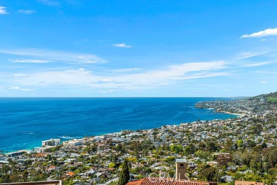 Dramatic Ocean View Architectural Masterpiece in Laguna Beach
Perched in one of Laguna Beach’s most breathtaking settings, this four-bedroom, three-and-a-half-bath architecturally rich residence offers endless Pacific Ocean views, from the shimmering waters by day to the dazzling coastal lights by night. Designed to maximize the panoramic scenery, retractable glass doors seamlessly merge indoor and outdoor living, inviting in the ocean breeze and framing the stunning vistas.
Spanning 4,951 square feet on a 6,500 square foot lot, this custom contemporary masterpiece is a sanctuary of style and sophistication. The open living spaces flow effortlessly to a spacious ocean-view terrace and a rare Laguna Hillside Garden, where outdoor seating, lush lawns, mature olive trees, and a vibrant flower garden create a serene retreat.
The chef-inspired kitchen is designed for function and beauty, offering top-tier appliances and stunning ocean views. A separate dining area provides a picturesque setting with views of the coastline and garden. The living space is designed for grand entertaining, enhanced by soaring ceilings, architectural art lighting, and generous gallery-like wall space.
A sculptural interior staircase and 100-year-old patinated maple flooring add to the home’s distinctive character. The temperature-controlled wine room, capable of storing up to 700 bottles, provides ample space for wine enthusiasts. The luxurious master suite features a private ocean-view balcony, spa-like bath, and his-and-her dressing areas. Two additional en suite guest rooms, both with ocean views, provide comfort and privacy. A convertible media room offers flexibility for additional living space.
Additional highlights include:
Elevator access to all levels
Oversized garage with a private gym
Whole-house audio and high-end finishes throughout
Multiple ocean-view decks, including a private master suite terrace with sweeping white-water, coastline, Catalina Island, and city-light views, this exceptional residence is a true coastal retreat, offering the best of Laguna Beach living.