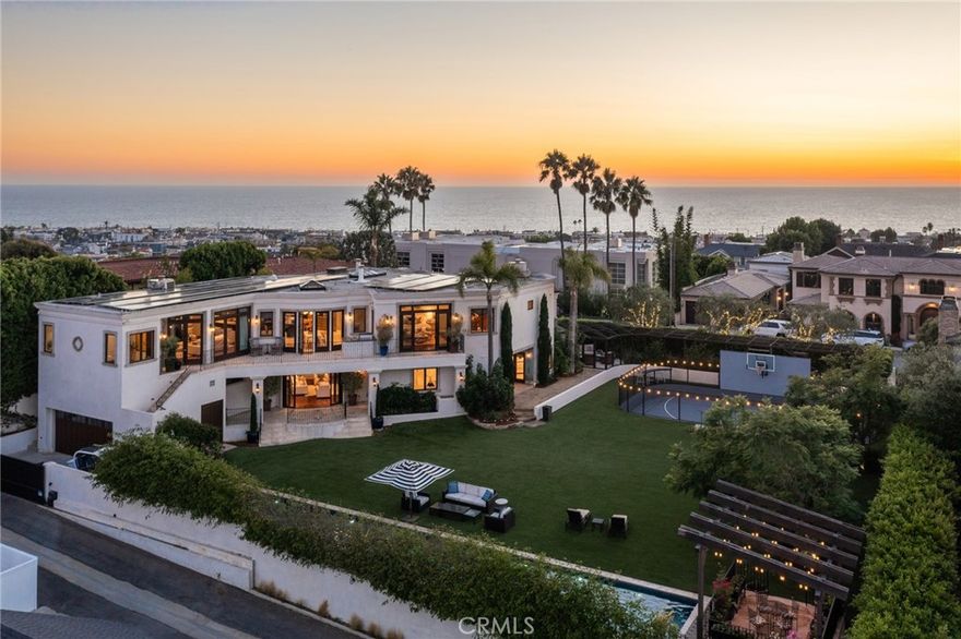 A truly one-of-a-kind property comes along once in a lifetime. Ideally situated on a hilltop in Manhattan Beach and encompassing nearly half an acre, this superior estate caters to the most discerning buyer.  Offering five bedrooms and six baths in 6604 square feet on a 20K+ square foot lot, this magnificent home features luxe materials and a myriad of indoor and outdoor spaces for luxurious living and entertaining.  Enter through the iron gates and into the dazzling entryway, grounded with inlaid travertine floors and a striking circular staircase; four bedrooms and baths offer serene private living quarters and spacious baths and closets.  A family room with onyx fireplace and a large custom bar opening to the courtyard offers impressive entertaining for family and friends alike.  The courtyard with a peaceful fountain and fireplace is the perfect spot for gathering or relaxing outside.  The breathtaking backyard includes an enormous lawn, regulation lap pool with inlaid fountains and a jacuzzi, a covered poolside terrace, and a full-size sport court, all grandfathered prior to SB 330 – a wondrous feature that cannot be duplicated in new construction. A below-ground, temperature-controlled wine cellar preserves your favorite vintages.  Dramatic views of downtown Los Angeles and the Santa Monica Mountains are obtained from several vantage points on the second floor, including a private balcony with outdoor barbecue.  The gourmet kitchen includes a huge central island with seating, cooktop, and sink; stainless appliances and dual ovens create a Chef’s atmosphere.  A casual dining area is adjacent, as well as a welcoming cozy family room with fireplace.  The formal dining room boasts a custom tray ceiling and ocean views and is bathed in natural light.  The decadent Primary Suite has sweeping city and mountain vistas, a fireplace, two custom closets with ample built-ins, a separate sitting room/office, and a well-appointed, spa-like bath with dual vanities, a soaking tub, and a fireplace.  A detached guest/office suite provides its own entrance and incredible views from the private second-floor balcony.  Stunning custom millwork and molding throughout, polished hardwood floors, bespoke cabinetry, a four-car garage, and a host of amenities make this a splendid home for family and friends or hosting lavish parties.  Perched on a hilltop in one of the most exclusive neighborhoods in Manhattan Beach, this property speaks for itself.