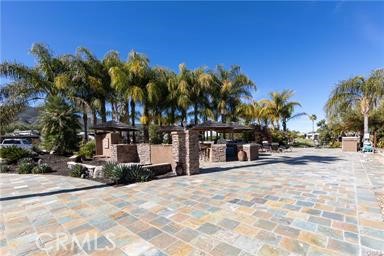 One of the best Rancho California RV Resort has to offer **The Corner Lot** This amazing, over-sized site with a tropical look and feel has always been a favorite and is rarely available. The entire lot combines flagstone tile with multiple palapa's covering a variety of cooking, dining and entertaining spaces throughout. Property features all of the appliances needed such as oven, dishwasher, microwave, sink, BBQ and washer/dryer! The front of the lot is used for living space featuring a flat panel TV, fireplace and water feature. Elegant built-in circular table palapa's are great for dining or just gathering with your favorite beverage! The spaciousness of the lot provides more parking spaces with a circular driveway than your typical lot. The rear of the site overlooks the golf course behind hole 8 tee box so no errant golf balls and has a beautiful water view! The lot is surrounded by lush landscaping that encloses the space for privacy and features great lighting for the evenings. This magical space provides the utmost enjoyment of the RV Resort lifestyle! This is a truly special space in a premier RV Resort located in SoCal minutes from Temecula Wine Country and close to San Diego, Oceanside and Palm Springs! Rancho California RV Resort offers a 14 hole PAR 3 executive golf course that is free for owners, (5) pools & jacuzzi areas, tennis courts, pickleball courts, laundry rooms, dog park, horseshoe lawn, exercise room, (2) clubhouses, hiking trails, grocery market all inside gated community that is guarded 24/7. *A MUST SEE* 2023 5th Wheel Solitude 2 bd 2 bath RV also for Sale. Package deal Available