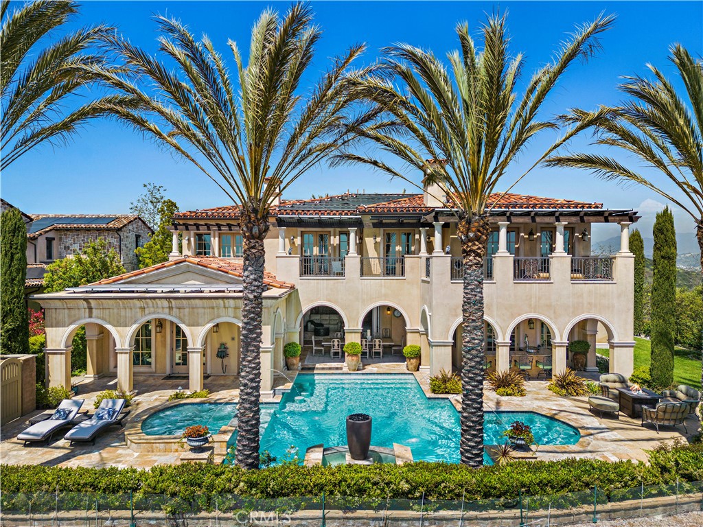 Embraced by the most coveted homesite at Covenant Hills in Ladera Ranch, this extraordinary custom estate provides unobstructed 300° panoramic views of permanent open space, gently rolling hills, shimmering evening lights and distant ocean views. These breathtaking vistas enrich both the grounds and most living areas of the ultra-private Italian Revival residence, which is located behind impressive gates at the end of a tranquil cul-de-sac with only one direct neighbor. Approximately 6,561 square feet, the luxurious villa reveals four ensuite bedrooms, each with a balcony or loggia and a walk-in closet, and five- and one-half baths. A grand entry hall with high ceiling, massive arched doors and a multi-tiered staircase offers an appropriately dramatic introduction. An oversized great room is the heart of the home, opening to the backyard and a chef-worthy kitchen with two islands, a walk-in pantry, nook, stone countertops, heated floors, farmhouse sink, built-in refrigerator and a six-burner Wolf range. In the adjacent family room, a glass wall system allows it to be closed off from the rest of the home while maintaining a visual connection. Those who enjoy memorable entertaining will appreciate the residence’s inclusion of a home theater with wet bar, motorized curtains, a big screen and terraced seating. Further enrichments include a home office with layered woodwork, a salon with built-in wash station, a gym and steam room that can become a fifth bedroom, and a formal dining room with oval coffered ceiling, soffit lighting and a wine-tasting area with built-in temperature-controlled wine storage. Framing views that can reach the ocean and Catalina Island on clear days, the sumptuous primary suite presents two balconies, a retreat, fireplace, walk-in closet, resort-inspired bath with heated floors, a wet bar and a mini refrigerator. Exquisite craftsmanship is demonstrated through the inclusion of cross-vault cloister ceilings, masterful woodwork, wood flooring, New Zealand wool carpet, extensive custom built-ins, & wood-framed archways. Solar power, smart-home tech, four-zone HVAC, whole-house and individual audio systems, and garage parking for four are also featured. Nearly 16,424 sqft, the desirable promontory is home to a five-star pool with jet-stream swim current, a bubbling spa, a spacious heated loggia with outdoor kitchen & grill, and a sit-down bar with tap service. A putting green, private motorcourt & a dog run are included.