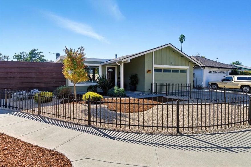 Why settle for a condo or townhouse with HOA fees when you can own a single-family home and enjoy private outdoor space! This 2-bed, 2-bath home offers +/- 1,196 sq. ft. on a +/- 4,000 sq. ft. corner lot, blending convenience, style, and low-maintenance living. The generous sized kitchen with granite counters, roll-out shelves, and freshly painted cabinets flows into the spacious dining area and living room, ideal for everyday living and entertaining. Sliding glass doors off the dining room open to the back patio and off living room leading to the large side yard, help fill the home with natural light. Both bathrooms are remodeled, and the primary suite has its own patio access. The front yard is framed by a wrought iron gate and fence, with new fencing along the front and side yard including a pergola with built-in bench. A large storage shed adds extra space, and the attached two-car garage is wired for 240V EV charging. Recessed lighting, laminate flooring, Nest thermostat and doorbell, drought-tolerant landscaping and freshly painted inside/out, help to enhance this bright, comfortable, low-maintenance home. Centrally located near commute routes and parks, this home combines comfort, convenience, and outdoor enjoyment, a perfect place to call home!