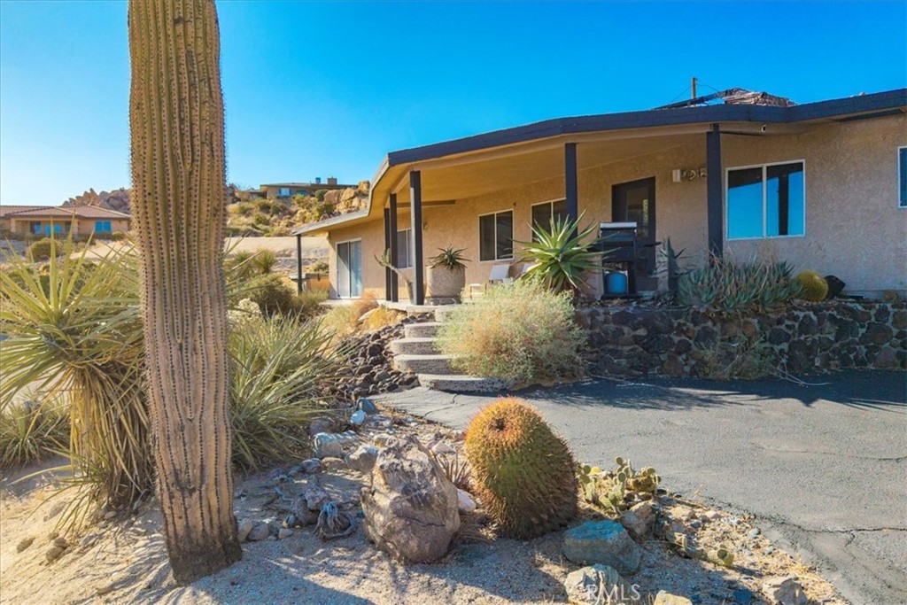 Tucked high in the coveted Western Hills Estates of Yucca Valley, this 2 bedroom, 1 bath gem offers privacy, perched among boulders with sweeping panoramic views and PAID/OWNED SOLAR. A long, private driveway leads to a secluded desert sanctuary where nature, character, and comfort come together beautifully. Step inside to find a home full of vintage charm—original architectural details, warm charismatic finishes, and mid-century desert vibes that are complemented by thoughtful modern updates throughout including a well though out, and more than generous walk in closet. The home features windows that frame the surrounding rock formations and expansive valley views and native vegetation, creating a connection between indoors and out. Outside, enjoy the magic of the high desert from a spacious patio ideal for entertaining, relaxing, or stargazing in total privacy. Whether you’re seeking a peaceful full-time residence, weekend escape, or a unique vacation rental, this one-of-a-kind property offers the perfect blend of retro charm, modern ease, and unmatched natural beauty. Just minutes from the heart of Yucca Valley and a short drive to Joshua Tree National Park, yet you feel a world away.