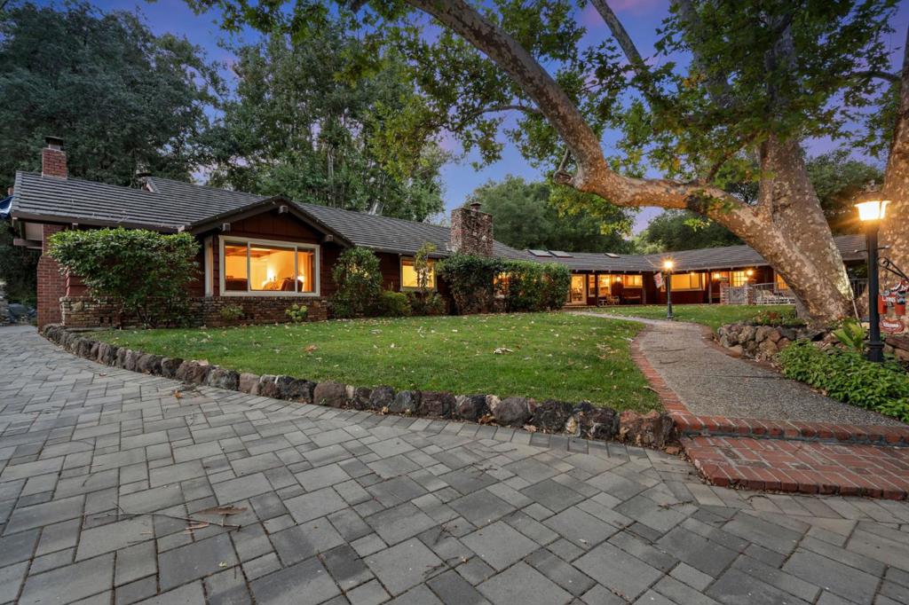 Welcome to 19405 Bainter Avenue a rare Saratoga retreat blending timeless charm, privacy, & opportunity. Set on over 2.6 acres of nearly flat, usable land, this estate offers unmatched potential, including lot split opportunities (buyer to verify). Easy driveway access or rear easement access. Tucked behind mature trees, the setting feels secluded while still being minutes from the heart of Saratoga & within award-winning Saratoga schools.The single-level main residence spans 3,700+ sq ft w/ 5 beds & 5 baths. Inside, enjoy vaulted ceilings, a spacious kitchen layout, and distinct bedroom wings with generously sized rooms. The homes rec room w/ bar and wine cellar provides the perfect place to relax & host. The grounds are equally captivating with a sparkling pool & spa, mature landscaping, and space to expand. A separate guest house w/ 2 beds & 2 baths offers flexibility for extended guest visits. Car enthusiasts will appreciate the 4-car garage + storage. Modern upgrades include solar panels with battery backup, offering efficiency and peace of mind. This is a once-in-a-generation property whether you're drawn to its vintage character, expansive grounds, or future development potential, 19405 Bainter Avenue is a rare find in Saratoga's premier location w/ top-rated schools.