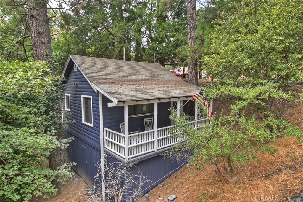 Beautifully updated Cape-Cod style cabin in the woods of Lake Gregory on a larger lot. The cabin has been updated floor to ceiling and inside and out. From electrical to plumbing (permitted of course) to flooring to walls to paint, appliances, lighting, and cabinetry!!! All while keeping that charm of cabin living. Ideally located near downtown and the lake making access to amenities easier to get to. Parking platform atop, space for two, with stairs down to the house. The home has a wonderfully covered entry deck with enough room for chairs and table to sit back and enjoy the nature around you. Stepping into the home you're immediately greeted by a beautiful vintage built in cupboards which are fantastic for housing all your wares for guests and entertaining needs. Living area on the left with room for dining and large windows for light. As you move forward the bedroom and bathroom are on the left with a galley style kitchen on the right. The bedroom is a suite style with the bathroom being wonderfully updated. The kitchen itself is surprisingly large and comfortable, with new appliances & cabinetry, and perfect for those who like to entertain. The kitchen steps out onto a large deck which is perfect for entertaining. The home itself is perfectly situated to give distance between you and the neighbors while capturing those forest views. A beautiful seasonal creek runs through the landscape as well. Down below there is a larger buildup that has plenty of storage space and tankless water heater. The home's foundation was also updated as well. Finally, there are plans available for those who would like to expand this charming cabin further. This is the charmer in the forest that everyone should take a moment to appreciate before it leaves.