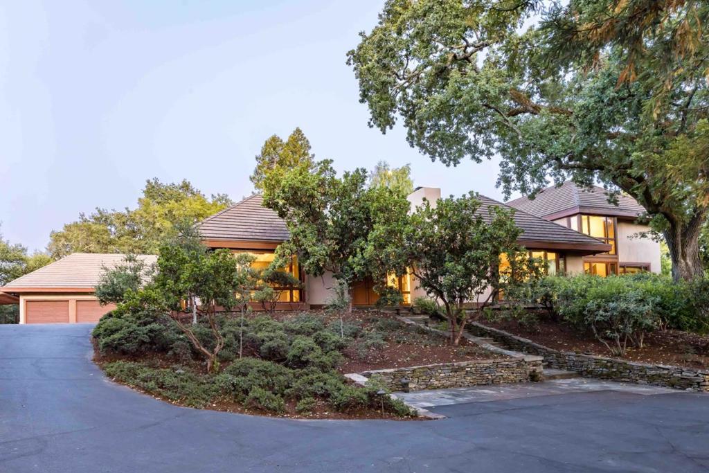 Set on more than 3.6 gated acres of quintessential Woodside grounds, this contemporary masterpiece is surrounded by towering oaks and lush greenery, offering a serene, woodsy retreat. The interiors reflect the natural setting with soaring cherry wood cathedral ceilings, mahogany floors, and expansive picture windows that flood the home with light and invite the outdoors in. Designed for both entertaining and everyday living, the residence features grand formal rooms, multiple fireplaces, a chefs kitchen with sunny breakfast nook, a walk-out family room, and a stylish executive office. Four bedrooms include a luxurious primary suite with its own fireplace, balcony, and spa-inspired bath. Outside, sprawling grounds offer a center courtyard with covered deck and fire pit, built-in grill, a separate guest house, and two garages including one with a lift for car enthusiasts as well as an RC car racetrack. Minutes from Portola Valley, top schools, and Silicon Valley tech centers.