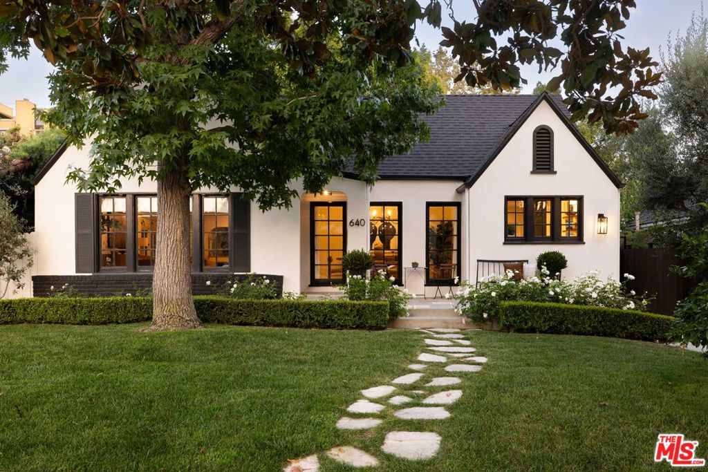 A chic 1922 English Tudor in Larchmont Village. Thoughtfully remodeled and upgraded by its current owners, this residence offers a welcoming retreat surrounded by lush greenery and romantic outdoor spaces, featuring a 3-bedroom, 2-bathroom main house plus a detached studio with laundry and full bath. The light-filled kitchen showcases elegant stone countertops, custom cabinetry, brass fixtures, Thermador appliances, and wraparound windows with direct access to the backyard. Formal dining room and spacious living room make a grand statement, with custom drapery and window coverings. Two charming guest bedrooms and a beautifully upgraded hall bath complement the sumptuous primary suite, which features a designer five-piece bathroom and dual closets. A private backyard offers multiple areas for relaxation and entertaining. Off the primary suite and second bedroom, French doors lead to an elevated patio framed by olive trees. The detached guest studio, featuring dual French doors, vaulted ceilings, and a full bath, makes for an ideal home office, creative space, or guest quarters. A grassy yard and graveled dining area set among mature trees complete this manicured oasis. Recent upgrades include a new roof and foundation improvements. Located in the sought-after Third Street Elementary, and a stroll to all the wonderful shops and restaurants in Larchmont Village that make this neighborhood so coveted.