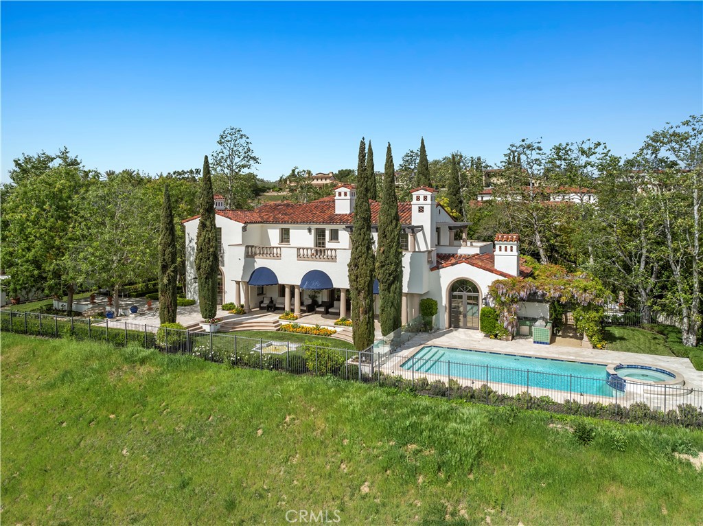 Reminiscent of the timeless villas along the Mediterranean coast, this front-row custom estate in Shady Canyon has been beautifully renovated to blend classic architecture with sophisticated, modern living. Set against the breathtaking backdrop of Bommer Canyon, the home offers an incredible 200 feet of sweeping scenic views-creating a private sanctuary designed for refined living and grand entertaining. From the sparkling pool and spa to the lush emerald lawn and multiple al fresco dining areas, every outdoor space is designed for year-round enjoyment. Framed by forever views from nearly every vantage point, this residence invites you to exhale and stay awhile. Step inside to a dramatic double-height foyer where arched hallways and custom wrought-iron railings frame a graceful, curved staircase. Natural light floods the interiors, drawing the eye to garden views beyond and setting the tone for the elegance found throughout. Spanning approximately 7,746 square feet across three levels-with convenient elevator access-the 5-bedroom, 7-bath estate showcases a serene neutral palette and wide-plank European oak flooring, creating a sense of cohesion and effortless elegance. The newly remodeled open-concept kitchen is the heart of the home, featuring designer cabinetry, premium appliances, and a large center island. It opens seamlessly to the family room and out to the backyard, where glass doors invite in light and canyon views-perfect for indoor-outdoor living and family gatherings. Upstairs, three spacious bedrooms include a serene primary suite with a private terrace, sitting area, and spa-inspired bath featuring dual vanities, a soaking tub, and walk-in marble shower. All baths have been recently reimagined with boutique hotel-level finishes and fixtures. The lower level is an entertainer’s dream-offering a game and media lounge with coffered ceilings, custom cabinetry, a built-in bar, and plush seating with a full projection screen for movie nights. Outside, the spirit of the Mediterranean continues with vine-draped loggias, a central courtyard with tiled fountain, and lush landscaping. Enjoy a built-in BBQ, pool, and spa-set against the undisturbed beauty of Bommer Canyon. Shady Canyon offers two 24-hour guard gates, clubhouse, swim, pickleball, tennis, hiking/biking trails, playground, and a world-class Golf Club.