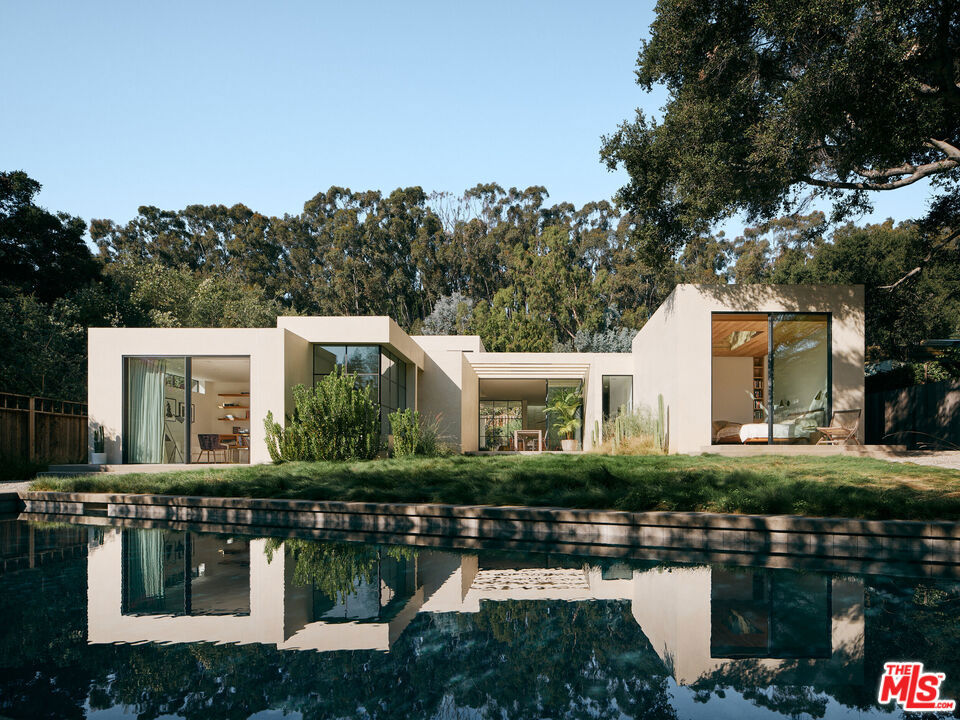 A Modern Hacienda -- The "Rustic Canyon" house. A home where light moves like a living thing, where architecture dissolves into nature, and where history meets innovation. Designed by Noah Walker of Walker Workshop, this modern hacienda in Rustic Canyon is a masterful blend of timeless warmth and contemporary simplicity a residence so compelling it has been featured in premier architectural and design publications, including Architectural Digest France, The Local Project, EST Living, World Architecture Design, Dezeen, and Denizen Magazine. The floor plan unfolds in four wings, each serving a distinct purpose: a primary suite, a children's wing, a guest suite with a theater, and a service wing with a garage. At the center, a glass-enclosed living and kitchen space acts as a light box, capturing the shifting glow of the sun throughout the day. There is never a moment when the home isn't illuminated in a magical way. The 15-foot-high kitchen ceiling, a true cathedral of gathering, is bathed in natural light and looks out to a grove of melaleuca trees. The primary suite, a sanctuary of calm, features a floating ceiling and a skylight that opens to the branches of a majestic coastal live oak. The smooth stucco exterior, softened by thoughtful shifts in height, creates moments where nature and architecture intertwine. Walker Workshop also served as general contractor, handcrafting key elements like the aluminum window system and custom furniture. Interior design by Lisa Petrazzolo, with art curated by Creative Art Partners, adds to the home's refined aesthetic. More than a residence, this is a living experience a seamless dialogue between light, texture, and time, set within one of LA's most storied and verdant enclaves.