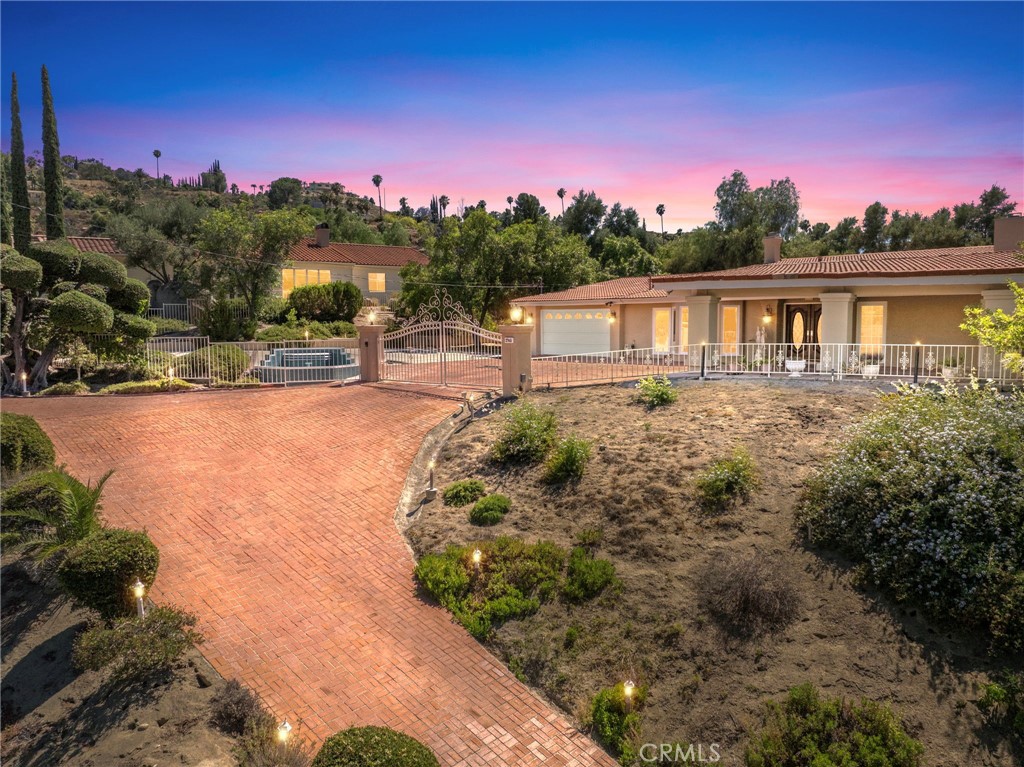 BACK ON THE MARKET! NEWER CERTIFIED SEPTIC! Surrounded by multiple pomegranate, peach, and citrus trees, this home, nestled on 1.1 acres of picturesque land, offers a seamless blend of elegance and functionality. Spanning 4,250 square feet of SINGLE STORY living space, this home is an EXTREMELY RARE find! As you enter the grand foyer adorned with a striking combination of Chinese and Italian tile, you are greeted with opulence at every turn! Two marble fireplace mantels add a touch of warmth and sophistication that complement the Italian murals, exquisite finishes and lovely wall paper throughout the residence. The heart of the home is its chef’s kitchen, meticulously designed for culinary enthusiasts. This kitchen has a ton of potential as it already features an elegant dining area with very large marble table strategically positioned in front of a large picture window, marble countertops, multiple appliances to include a double refrigerator, electric and gas cooktops, double ovens, as well as dual pantries, and abundant storage with pull-out drawers for dishes and smaller kitchen appliances, as well as glass cabinets to showcase your cherished pieces. The home is complete with a formal living room and a formal dining room, both waiting behind French Doors, and a spacious family room, all presenting magnificent chandeliers to captivate your guests! With five bedrooms and three and a half bathrooms, including a master ensuite that exudes tranquility and comfort, the home provides all of the space for any living situation and even has ample closet space to meet storage needs. Entertain effortlessly on the expansive outdoor brick patio, perfect for large events, which spans the length of the home and offers breathtaking views of the surrounding mountains, OR spend time on the beautiful green, shady side-yard with a second outdoor patio and fire pit, both perfect for hosting gatherings or enjoying serene moments outdoors. Additional features include: A lighted brick driveway on timers, a sprinkler system around the property, and covered approach and space for ample outdoor parking (at least 6 vehicles) and a two-car garage with maximum cabinet storage to ensure both convenience and organization. Take a look at this executive home today to discover unparalleled design and unlimited potential for your own personal touches in this Mediterranean-inspired sanctuary!