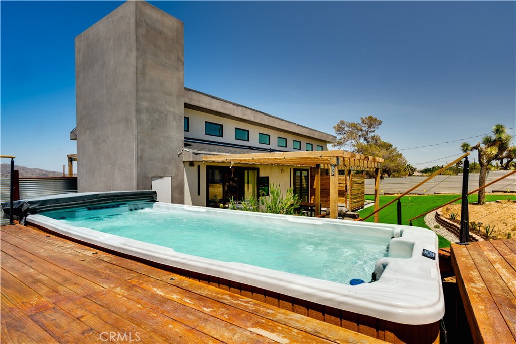 Custom-built in 2023, this stunning Upper Friendly Hills home offers sweeping views of Joshua Tree with soaring 12–16’ ceilings and walls of Milgard picture windows and French doors that bring the outdoors in. The open layout features polished concrete floors, tongue-and-groove cedar ceilings, and butcher block counters for a warm, organic feel. The kitchen comes with new stainless appliances, while the spa-style bath includes a custom double vanity with Indonesian stone sinks, a floor-to-ceiling tiled shower, and steam sauna. Resort-style outdoor living includes a custom 9-hole putting green and a massive 19’ long swim spa, perfect for entertaining, recreation, and stargazing. With fully paid solar, energy-efficient 6’ walls, and stylish furnishings included, this home is move-in ready. Located minutes from the National Park entrance, downtown Joshua Tree, and Pappy & Harriet’s, this is the ideal desert retreat or full-time residence.