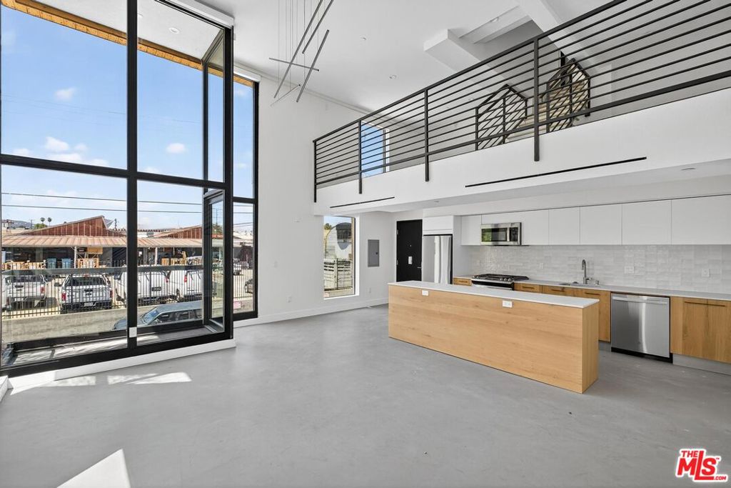Here in what's known as Frogtown, a slice of Los Angeles alongside the river, is a new building. These are live/work lofts, designed for a life built to be both efficient and inspired. The space is defined by clean lines and unblemished surfaces, with floor-to-ceiling windows that not only bring the world in but also frame it beautifully. Inside, you'll find a modern kitchen and two and a half bathrooms. The layout includes a bedroom loft and a main bedroom that opens directly onto a private patio. For convenience, a washer/dryer and dishwasher are tucked away in the kitchen area. The building provides peace of mind with gated parking and electronic entry. The private patio offers a quiet escape. From there, you can observe the true character of the city, the warehouses and power lines well as the river that gives the neighborhood its identity. Located in the heart of Frogtown, you're just moments away from the best of the Eastside.