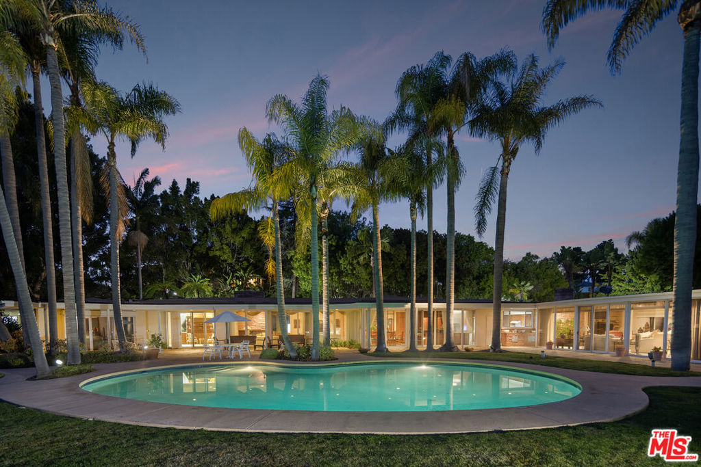 Set behind private gates in prime Lower Bel Air, this quintessential mid-century modern estate spans an expansive, beautifully landscaped lot, offering a rare blend of seclusion, architectural charm, and effortless indoor-outdoor living. A tranquil reflecting pool with a cascading waterfall sets a serene tone at the entrance, while lush pathways lined with fruit trees lead to the heart of the property. A large motor court and gated driveway provide a stately approach, complete with a two-car garage and two separate studio spaces, each with its own bath, offering flexibility for guest accommodations or creative workspaces. Inside, sun-drenched interiors unfold across a single-level floor plan, where walls of sliding glass doors seamlessly integrate the indoors with the outdoors. The main living room, anchored by a classic stone fireplace, opens directly to the backyard, setting the stage for both grand entertaining and intimate gatherings. A library sitting room, formal dining room with a built-in bar, and sprawling rec room enhance the home's effortless flow, while the strategically placed bedrooms, each with direct outdoor access, maximize privacy and natural light. Outside, a classic kidney-shaped pool framed by sprawling flat lawns and towering palm trees creates a scene reminiscent of a Slim Aarons photograph, while a wraparound covered patio offers the perfect setting for lounging, dining, and year-round entertaining. Enveloped by mature landscaping and lush greenery, the estate feels like a private oasis in one of Los Angeles' most coveted enclaves. Whether embraced in its current mid-century elegance or reimagined into a world-class estate, the perfectly flat grounds offer limitless potential for future expansion or redevelopment, making this a truly rare opportunity to own an architectural gem with both immediate livability and immense long-term value. Additionally, 259 St. Pierre, directly neighboring the estate, is also available, offering the option to acquire an unprecedented 3.8-acre legacy estate in one of the most prestigious enclaves in the city. A property of this magnitude is more than a residence it is a statement of history, scale, and exclusivity, an opportunity that will likely never be replicated.