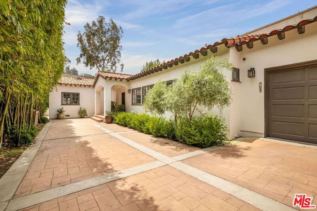 Tucked at the end of a quiet cul-de-sac in Silver Lake, this Spanish-style home sits on a generous gated lot, walking distance to the lake and park. The single-story residence features soaring ceilings and an open floor plan anchored by a chef's kitchen with custom quarter-sawn white oak cabinetry, Calacatta Gold marble counters, Zellige tile, and a built-in dining nook. Top-tier appliances, including a Sub-Zero refrigerator and Wolf range, complete the space. The living area is framed by bespoke oak bookcases and flows easily for entertaining. Three bedrooms include a spacious primary suite with direct access to the outdoor retreat. The home offers multiple outdoor entertaining areas from the front yard's gas fireplace to new TimberTech decking framed by Spanish-style railings in the backyard. Additional amenities include a finished two-car garage with EV charging, Sonos sound system, a full Lutron lighting system, and easy access to some of the best neighborhood cafes, restaurants, and parks Silver Lake has to offer.