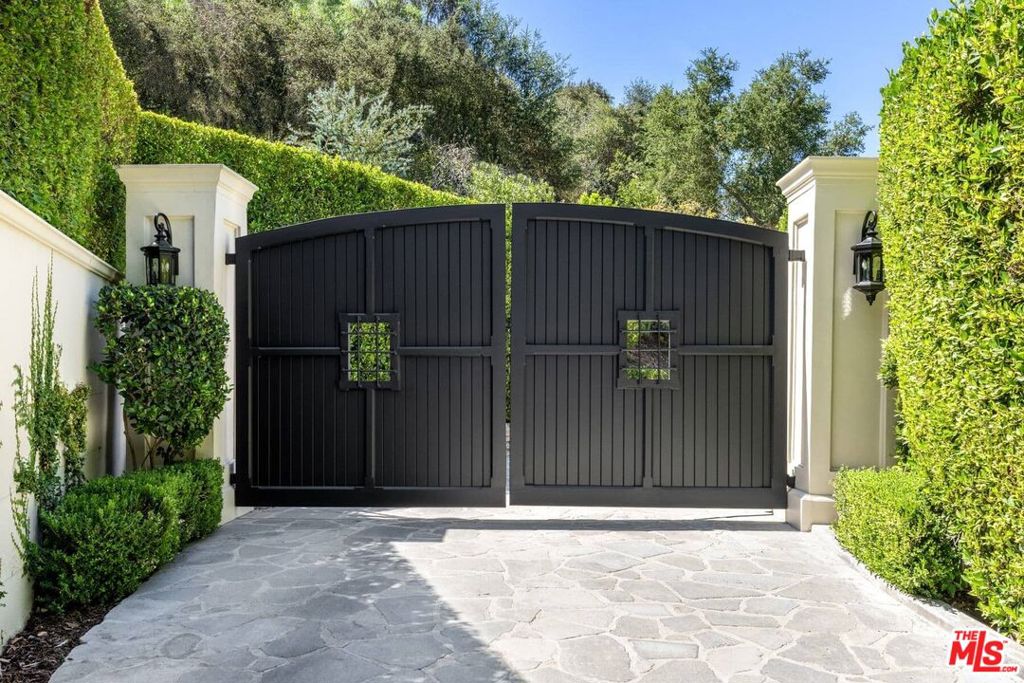 One of the most private and special homes in the exclusive guarded celebrity enclave of Hidden Valley Road in Beverly Hills. Incredible 1/4 mile treelined drive with massive gates leads to an exquisite designer contemporary regency style surrounded by a forest of parkland and nature elements. Beautiful sky-lit entry gallery, step down living room with fireplace and views of expansive lawn, infinity pool and spectacular trees. Outdoor dining room terrace with vast views. Romantic master suite with fireplace, beautiful marble bath, double closets and large garden terrace. Wood paneled library with fireplace opens to terrace. 3 additional bedroom suites and optional 4th with bath. Lower level media/family room. Private hiking trails to enjoy and Franklin Canyon trails direct within the neighborhood. Large sky-lit gym, sauna, cold plunge and shower. A rare and uncommon private environment surrounded by peaceful nature yet moments from the best Beverly Hills has to offer. Parking for dozens of cars, on site security.