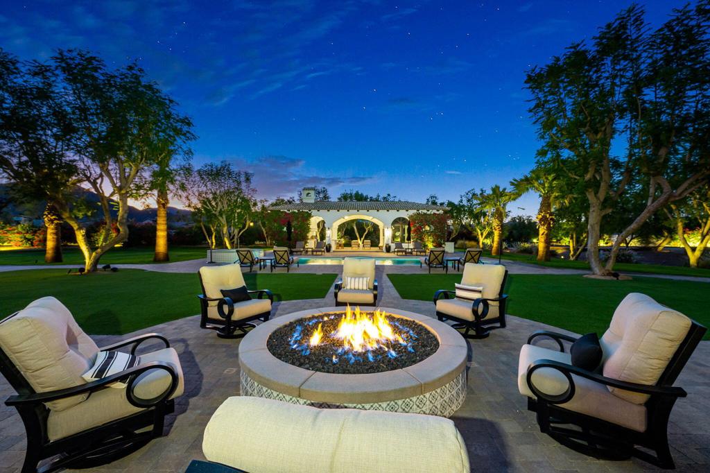 An opportunity to take advantage of rare price improvement in the gated enclave of La Quinta Polo Estates! A luxury estate of uncompromised beauty on over 2 acres and with 7 bedrooms, is a private sanctuary and ones' personal resort with stone walkways, mature palm and citrus trees, bougainvillea, water fountain, swimming pool, spa and firepit, lounge areas and a fireplace. Even a playground for children! The main residence exudes character, with 3 fireplaces, and architecturally designed, interior features such as custom hand hewed beams , doors, windows and floors, built on the site at the time of construction. 4 en-suite bedrooms, each has stately French doors giving access to the loggia and manicured grounds. The heart of the house, the kitchen, connects the living room with the formal dining room and the adjacent walk-in bar for seamless entertaining. A large, private casita can be found at the end of the main residence, with a kitchenette, primary and secondary bedroom, and attached laundry room. Separately, a second guest house resides near an outdoor kitchen and lounge, pool and spa. For gourmet cooks and lovers of entertaining, a custom designed outdoor chef's kitchen pavilion is fully staffed with barbecue, grill, refrigerator, a pizza oven, overhead, built-in heaters, a TV and music, bar seating for 12 and a dining patio for 20 or more. And much, much more. Every possible detail or want has been executed in this impossibly beautiful estate. Numerous major improvements have been completed in 2023 and 2024, a comprehensive list is available upon request. Turnkey Furnished without exception.