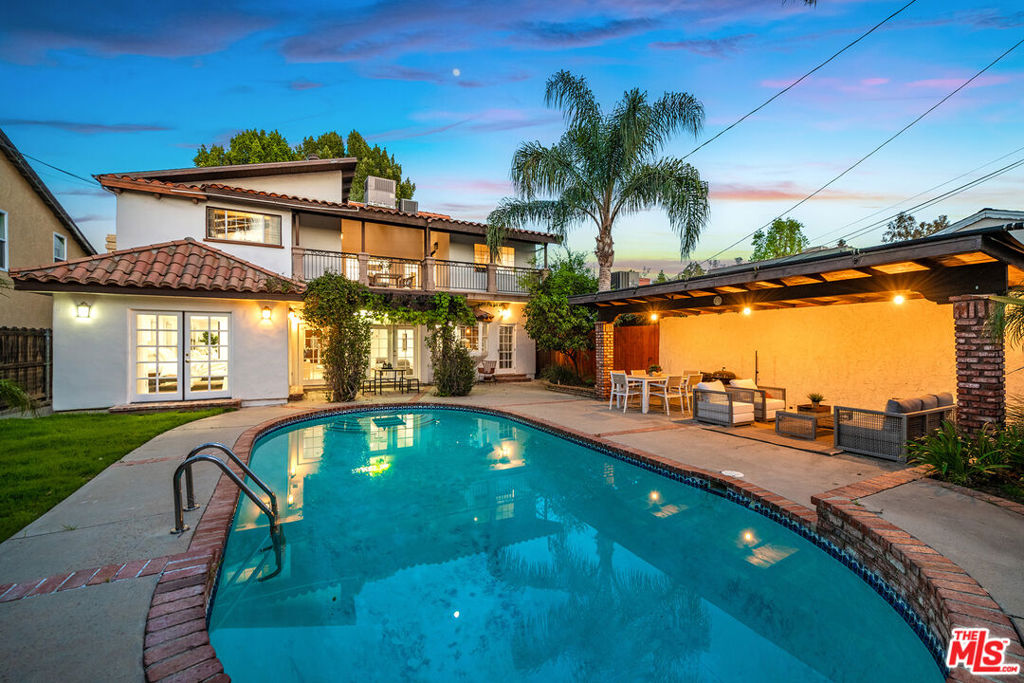 Welcome to 4115 Laurelgrove Avenue, an elegant Mediterranean-inspired retreat nestled in the prestigious Footbridge Square neighborhood. Behind private gates on a manicured 6,491 sq ft lot, this sophisticated 5-bedroom, 3.5-bathroom residence offers 3,236 sq ft of refined living space. Step inside to discover soaring ceilings, rich hardwood floors, and sun-drenched interiors designed for effortless luxury. The gourmet kitchen boasts sleek cabinetry and stone countertops, seamlessly connecting to expansive living and dining areas anchored by a stylish fireplace. The primary suite is a sanctuary with its own fireplace, oversized walk-in closet, and spa-like bath with a soaking tub and dual vanities. A separate-entry fifth bedroom offers flexible use as a guest suite, office, or studio. Enjoy a tranquil backyard oasis with a sparkling pool, spa, multiple patios, and mature landscaping. Additional features include a family room with projector, and a two-car garage all in a quiet, coveted enclave near the highly sought-after Carpenter School District just moments from Ventura Blvd's best shops, dining, and studios. This is Studio City living at its finest.