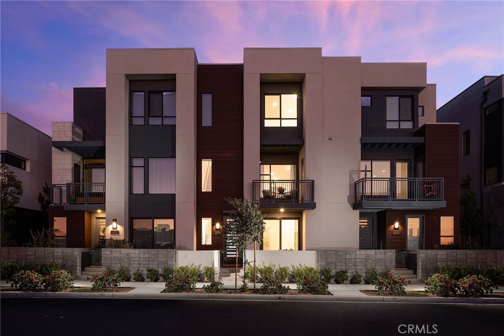 This newly built luxury townhome in The Landing at Tustin Legacy offers the perfect blend of modern sophistication and everyday convenience in one of Orange County's most desirable new communities. Completed in 2023, this light-filled contemporary home welcomes you with an open-concept layout featuring soaring 12-foot ceilings, imported Italian stone floors, and sleek matte black designer finishes that create an atmosphere of understated elegance. Enter the 3-story plan through the thoughtfully designed lower level that includes an ensuite bedroom (or optional office or fitness room) and direct access to the two-car garage. This space also opens directly to a sunny patio, bringing the outdoors in and making for a welcoming curb appeal. Large windows fill the second-level great room with natural light, creating an ideal environment for both entertaining guests and everyday relaxation. The living room flows seamlessly to a private balcony, extending your living area outdoors. The luxe chef's kitchen is finished with full-height maple cabinetry, a complete stainless steel JennAir/KitchenAid appliance suite, and a striking quartz island ready for casual bites and conversation. Upstairs, two generously sized bedrooms each provide ample accommodation with large windows and spacious closets. The primary suite serves as a true retreat, with two walk-in closets featuring professional organizers and a spa-like bathroom with double sink vanity and oversized shower. Modern convenience is built-in, with smart features including paid solar panels, an EV charger, Google Home smart system, instant hot water system, and SpringWell whole-home water filtration system. This property’s excellent location within The Landing community provides views of Disneyland fireworks displays and John Wayne Airport, while being within the boundaries of top-rated Tustin Unified schools. All within walking distance of The District shopping center and entertainment, local parks, and a diverse array of restaurants, creating a lifestyle where luxury living meets unmatched convenience in the exciting heart of Tustin Legacy.
