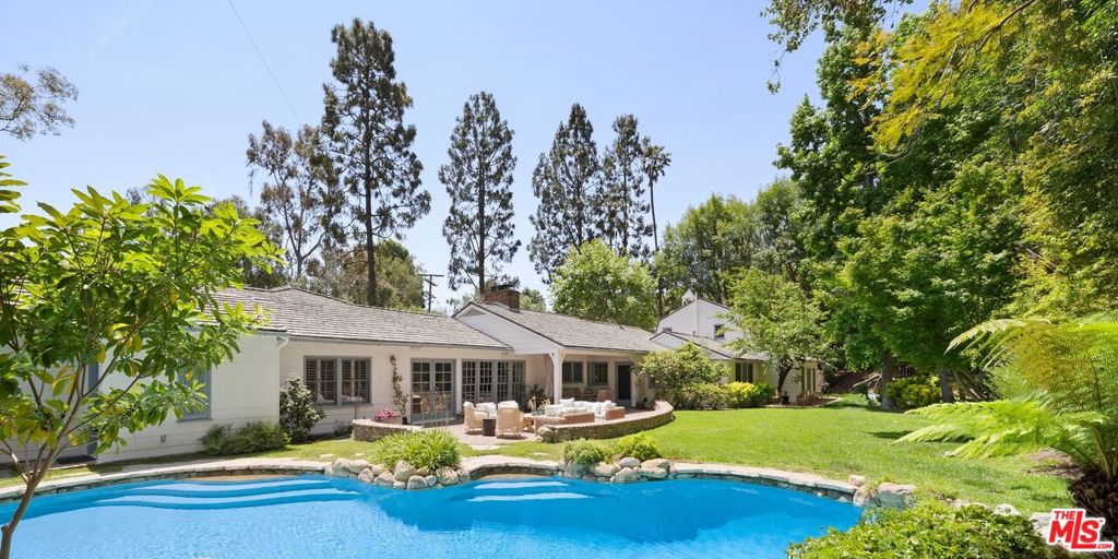 A Storybook Brentwood Traditional with Magical Grounds Tucked away on over two-thirds of an acre in the idyllic celebrity neighborhood of Lower Mandeville Canyon, this enchanting Brentwood traditional feels like a page from a Nancy Meyer's film where every room tells a story and every garden path leads to something beautiful in this 6 bed 6 bath home. Nearly 5,000 square feet of sunlit interiors welcome you with refined yet relaxed elegance, which include an open-space gourmet kitchen with a sun-drenched built-in breakfast area and family room, a cozy and spacious wood-paneled dining room with fireplace, and a light-filled living room with vaulted ceilings all open to the blooming and expansive backyard. Green and lush with mature trees, florals and winding stone paths creating an atmosphere that's both serene and cinematic. The romantic primary suite offers a peaceful sitting area, luxurious bathroom, dual walk-in closets and sauna. A fully contained one-bedroom guest house with living room, kitchen, bathroom and laundry, tucked amidst the greenery offers privacy and endless charm for guests, work, or creative pursuits. A fabled retreat tucked away on a sprawling, verdant lot, offering an ultra-private escape with effortless access to Brentwood's vibrant shops, cafes, and culture.