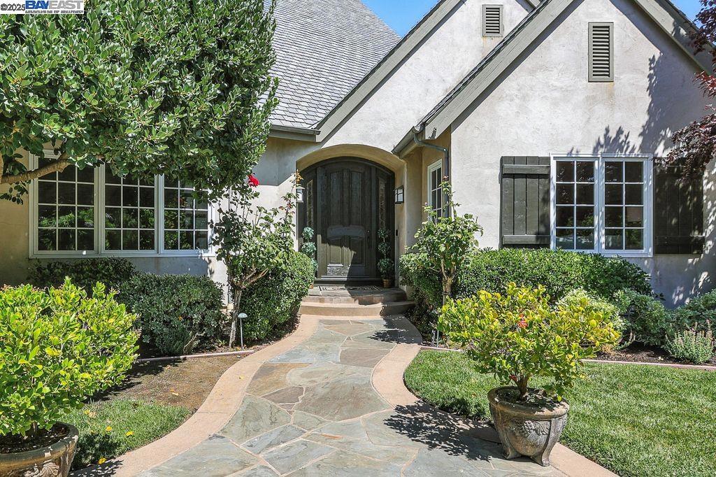Exuding timeless sophistication, this French Country-inspired residence is set within the prestigious gated community of Ruby Hill. A grand interior reveals travertine marble floors, soaring vaulted ceilings with exposed beams, and a stately gas fireplace. The formal dining room features rich hickory hardwood, while the elegant family room offers a custom wood-burning fireplace, built-in cabinetry, and French doors opening to serene garden views. The chef’s kitchen is a masterpiece, appointed with maple cabinetry, Taj Mahal quartz countertops, premium stainless steel appliances, walk-in pantry, wine cellar, and a charming breakfast nook. A main-level ensuite bedroom with private patio access offers luxury and privacy, complemented by an executive office with custom cabinetry and Australian hardwood floors. Upstairs, the opulent primary suite boasts a gas fireplace, private balcony, spa-like bath, and a generous walk-in closet along with 2 bedrooms + a bonus room that can be utilized as a 5th bedroom. The lushly landscaped grounds include mature trees, vibrant gardens, and an infinity lawn overlooking the 1st hole of Ruby Hill Golf Course. Enjoy exclusive access to resort-style amenities and top-rated Pleasanton schools in one of the East Bay’s most coveted communities.