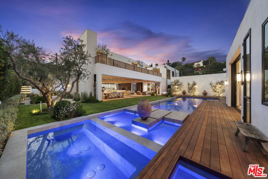 "FIVE FATHOMS"- The latest creation by celebrity designer Jae Omar and architect Eran Gispan, is a residence of lyrical beauty and organic architectural reverence. Set on a sprawling 20,000 square foot lot, this 9,800 square foot residence unfolds across five distinct structures, thoughtfully connected by glass-encased walkways that 'float' over meandering waterways. The interior aesthetic showcases Omar's signature 'organic modern' approach, featuring a textural symphony of sandblasted stone, vanishing walls of glass, and meticulously crafted white oak accents that converge in perfect harmony. The primary suite stands as a singular retreat, complete with a private library, a vast deck, and an ethereal stone-wrapped bathroom that is cloaked in natural light from strategic skylights that continue into the custom walk-in closets. Additional features include ADU, conceived as a serene wellness retreat, a 65-foot swimming pool adorned with a grand spa and cold plunge, expansive cobblestone terraces, multiple outdoor fireplaces, a fully equipped alfresco kitchen, state-of-the-art Dolby theatre and a cutting-edge security system with voice-activated infrared technology. 'FIVE FATHOMS' - A legacy of contemporary design and luxury living!