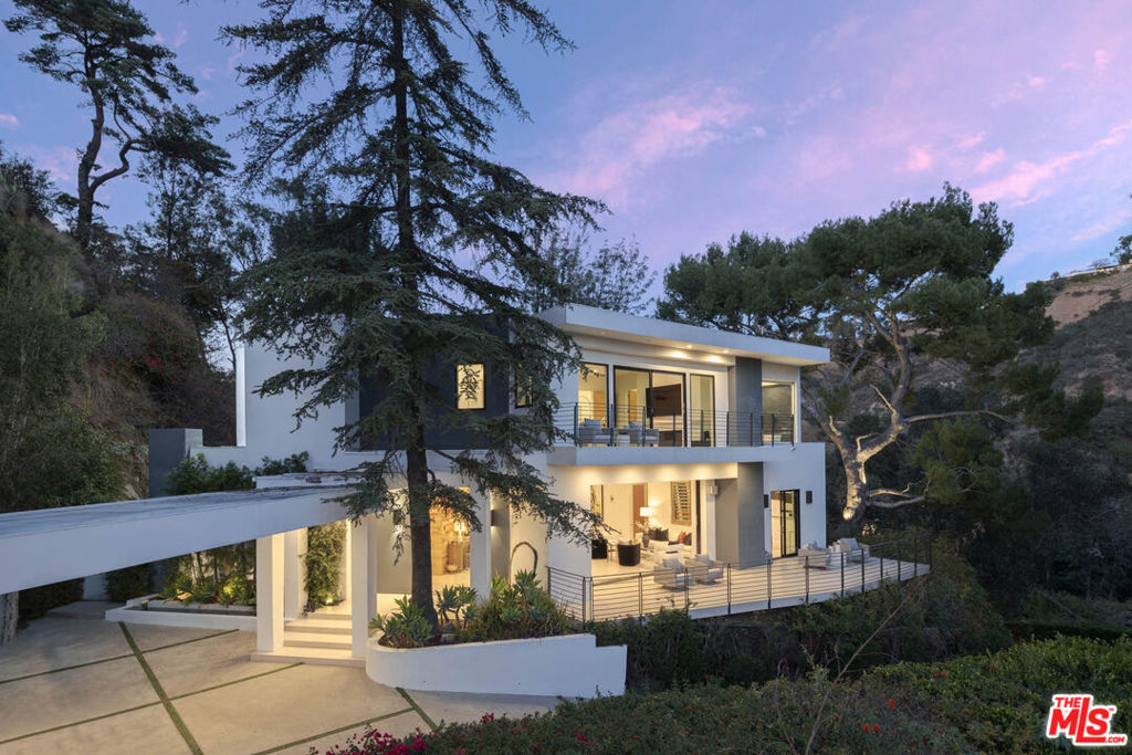 Drenched in sun, this dramatic modern retreat overlooks Nichols Canyon. A gated private driveway is your entree into a vibrant open-air compound designed to stimulate your senses and elevate your spirit with 360 degree views. Open living spaces and expansive floor to ceiling glass connect you with the beauty of your natural surroundings. Enjoy the bright living spaces, large balconies and lounging sun deck while basking in the sun by the refreshing pool and outdoor TV area. The surround sound movie theater awaits those movie enthusiasts with all the at home conveniences. Two primary suites and three additional bedrooms await you and your guests when you are ready to retire for the evening. The detached guest house can be used as a private retreat or could be transformed into work space or private gym. This over 6,000 square foot smart home is situated on nearly an acre lot above the magic and serenity of Hollywood Hills.