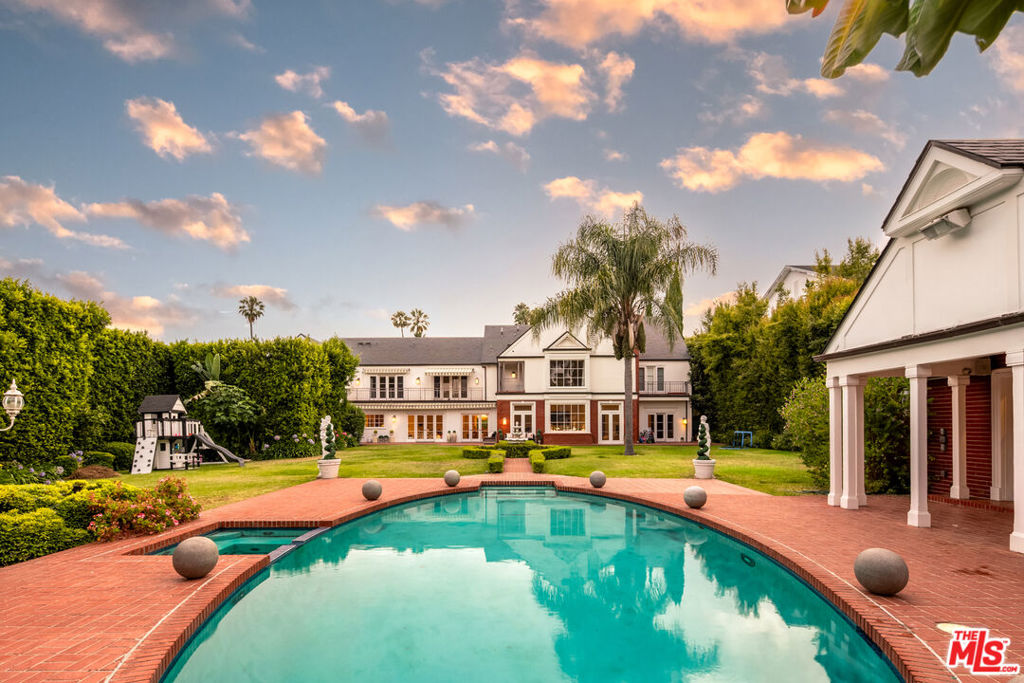 A Gated traditional estate set on park-like grounds sprawled across a 30,000+ sqft lot on prime 800 block of Rodeo Drive in the Beverly Hills Flats. Moments from the Beverly Hills Hotel, with an 8 car motor court and 3-car garage, 804 N Rodeo offers nearly 8,000 square feet of grand interiors including a double-height foyer, formal living and dining rooms, a paneled library, and a sunlit family room that opens directly to the backyard. French doors connect nearly every space to the grounds. Primary suite with his and hers bathrooms and closets, with sauna and steam room. Four ensuite bedrooms upstairs with generous volume are connected by a continuous balcony, each room positioned to take in views of the opulent gardens below. The kitchen is equipped with Wolf appliances and two of everything, custom cabinetry, a large central island, with an adjacent breakfast nook and butlers pantry. The backyard is centered by a tiered fountain and features an oval pool and spa framed in red brick. Manicured boxwood hedges, mature trees, and a curated rose garden define the landscape, while a columned pavilion, built-in BBQ, and full outdoor kitchen create a setting designed for effortless entertaining. A freestanding guest house sits beyond the pool with a full bathroom plus a bonus 1-car garage. An exclusive setting with one of the city's most prestigious addresses.