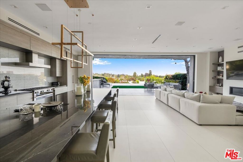 A modern masterpiece with sweeping, unobstructed views from the hills to the city skyline, 12311 11th Helena Drive sits quietly at the end of Brentwood's most iconic and private cul-de-sac. Built in 2020 and fully customized with top-tier finishes, this 5-bedroom, 6-bathroom architectural gem spans 6,245 square feet on an all-usable 11,000 square foot lot on the coveted rim side of Helena Drive. Ideally positioned south of Sunset and north of San Vicente, the property offers rare walkability to Brentwood's best restaurants, shops, and cafes while enjoying total privacy and striking vistas. Tucked into the back of the cul-de-sac with a detached front-facing garage, the home welcomes you into beautifully scaled interiors featuring 11-foot ceilings, a dramatic 25-foot skylight, and thoughtfully curated custom materials throughout. Floor-to-ceiling pocket doors open to a resort-like backyard complete with an infinity-edge pool, elevated spa, built-in BBQ with stone counters and single sink, outdoor fire pit, and a large flat grassy lawn - all capturing spectacular city and canyon views. Beneath the pool level sits a full private gym and a hidden sports court, creating a true all-in-one lifestyle retreat. The main level features two spacious en-suite bedrooms, a powder room, a laundry room, and expansive open-concept living and dining spaces designed for entertaining. A custom wine room and Miele kitchen equipped with dual ovens, built-in coffee stations, and seamless cabinetry anchor the home's central gathering spaces. All smart features, including lighting, security, temperature, and audio, are individually app-controlled. Upstairs, three additional en-suite bedrooms surround a floating loft lounge and sun-filled front-facing balcony. The primary suite is a true sanctuary with floor-to-ceiling windows, a sleek fireplace, and stunning panoramic views. The spa-inspired bathroom features a soaking tub, two water closets, dual vanities, and an oversized walk-in closet all finished with bespoke detailing. Thoughtfully designed, fully turnkey, and built to capture light, views, and comfort at every turn 12311 11th Helena Drive is a rare offering in one of Brentwood's most desirable and timeless locations.