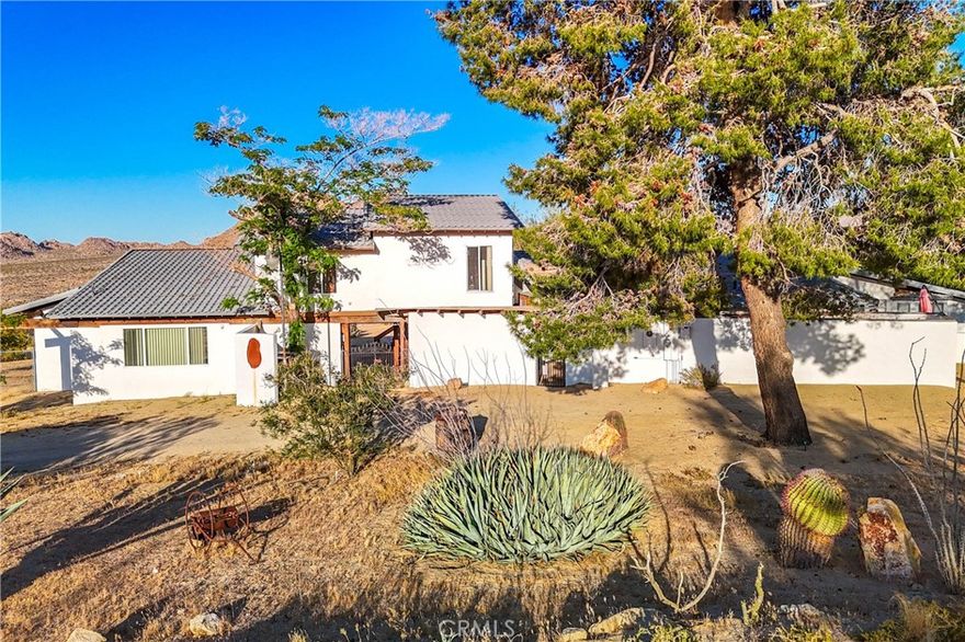 TWO JOSHUA TREE HIGHLANDS PROPERTIES TOTALING 10 ACRES! A nature lover’s delight, featuring breathtaking views, this enchanting desert refuge is an easy hike to a 900+ acre desert preserve and a short drive to the Joshua Tree National Park entrance. The main house, a remarkable 2-bedroom, 2-bath entertainer’s dream with a welcoming guest quarters, is situated on 5 acres, while the adjacent 5 acres is vacant and ready for buyers to unleash their architectural vision. Comfort and style intersect in the primary home, which boasts a vast, open concept living space. The modern chef’s kitchen with sparkling granite countertops and stainless-steel appliances opens into an expansive dining and entertaining area. The beautifully exposed wood beams and trusses lend a warm, inviting ambience. A versatile yoga room or office provides additional flex space for relaxation or accommodating overnight guests, who can also enjoy the privacy of the adjacent guest house--a spacious studio bedroom with a bathroom which offers the perfect retreat for friends or family. Year-round comfort and customized climate control is assured with 3 zoned mini-split HVAC, a large Mastercool evaporative cooler and cozy pellet stove. The 10 KW paid ground-mounted solar array ensures energy needs are effortlessly met, with electric bills virtually nonexistent. Outside, the allure continues with metal tile roofing, towering pines and Joshua Trees, and a sprawling view deck, ideal for alfresco dining or entertaining against the backdrop of wondrous vistas. Enjoy tranquility in the newer spa while stargazing and listening to coyotes keen in the distance. As if that weren't enough, your purchase includes the adjacent 5-acre parcel on the north side, complete with perc test and site prep work already completed, including a survey. This is a phenomenal deal! Your oasis awaits—schedule your private tour today!